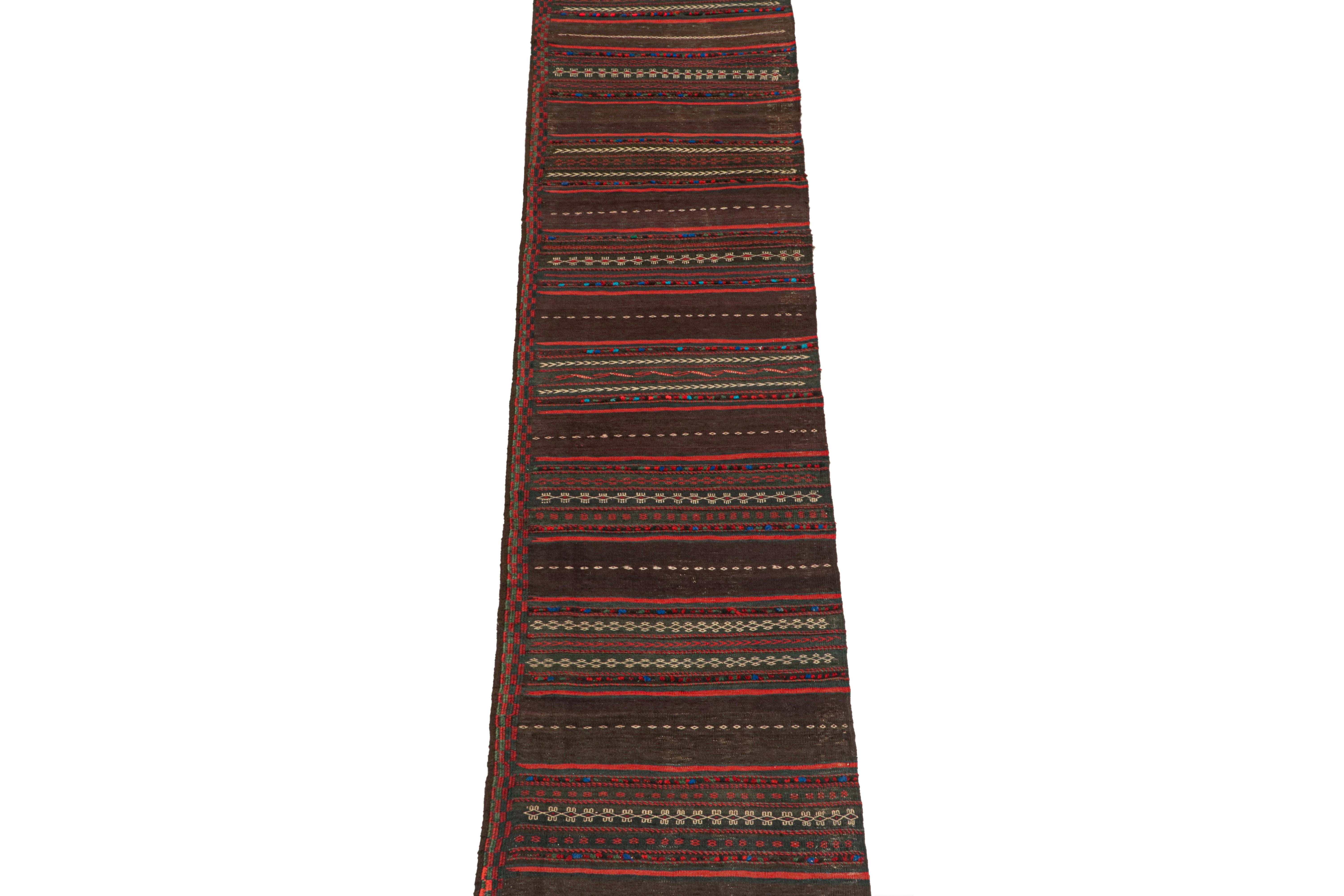 This vintage 2x10 Persian kilim runner is handwoven in wool, and originates circa 1950-1960.

On the Design:

This design enjoys a deep aubergine purple with more vibrant red stripes and other complementary primary colors. There’s a rich brown