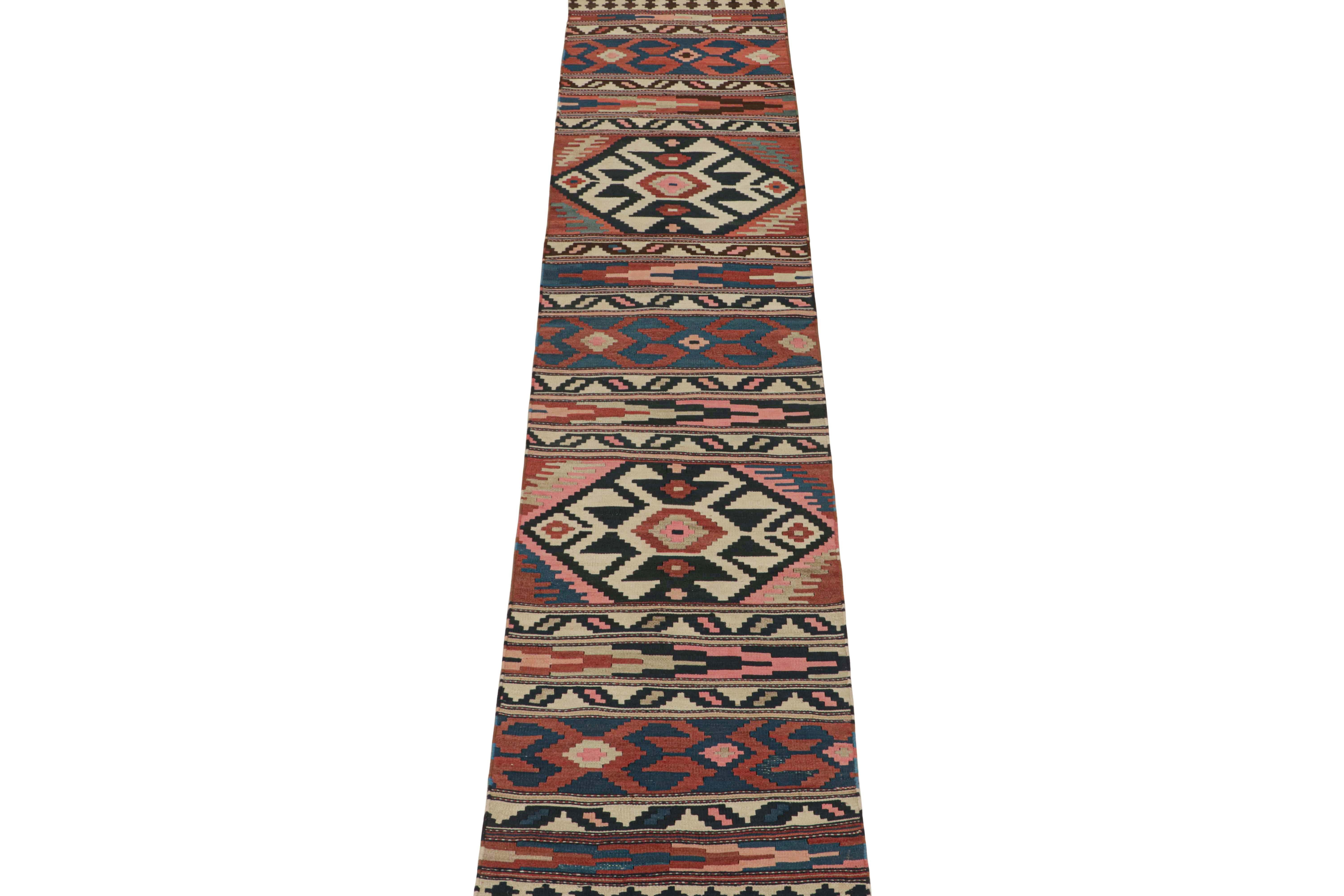 This vintage 3x12 Persian kilim is believed to be a Shahsavan runner of mid-century design—handwoven in wool circa 1950-1960.

This design favors navy blue, black, off-white and red geometric patterns, but keen eyes will further admire bright pink