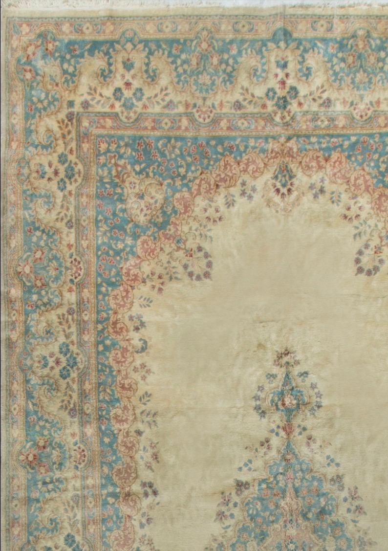 Tappeto persiano vintage Kirman tessuto a mano del 1940 circa con il classico campo avorio circondato da bordi blu polvere. Misure: 9'6