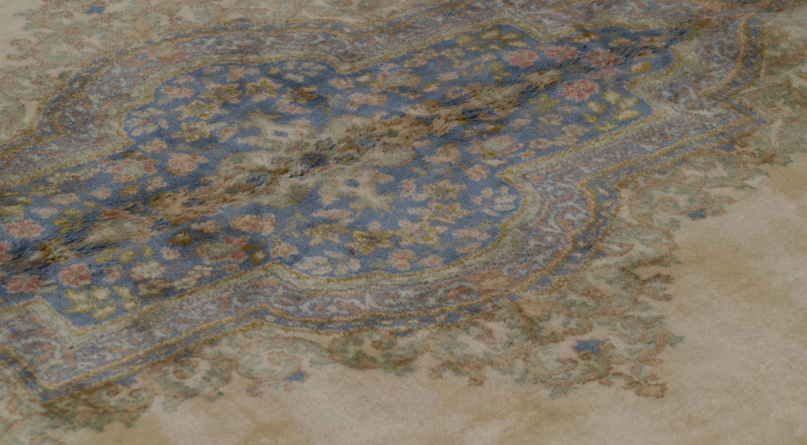 Ein reizvoller Kerman-Teppich, der mit exquisiten Details gewebt wurde. Der rote Grund ist mit gewebten Blumenmustern gefüllt, die ein zentrales elfenbeinfarbenes und zartblaues Medaillon umgeben, das von einer zartgrünen Hauptbordüre und
