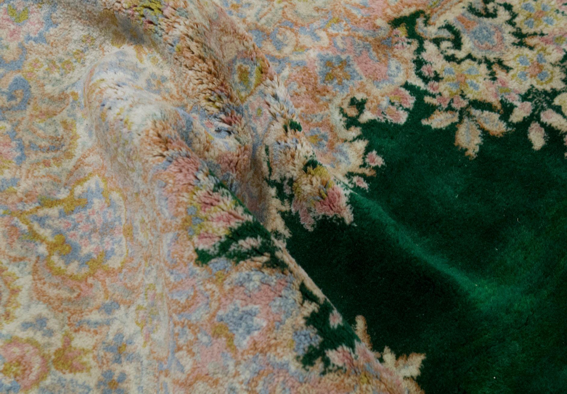 Ein reizvoller Kerman-Teppich, der mit exquisiten Details gewebt wurde. Der rote Grund ist mit gewebten Blumenmustern gefüllt, die ein zentrales elfenbeinfarbenes und zartblaues Medaillon umgeben, das von einer zartgrünen Hauptbordüre und