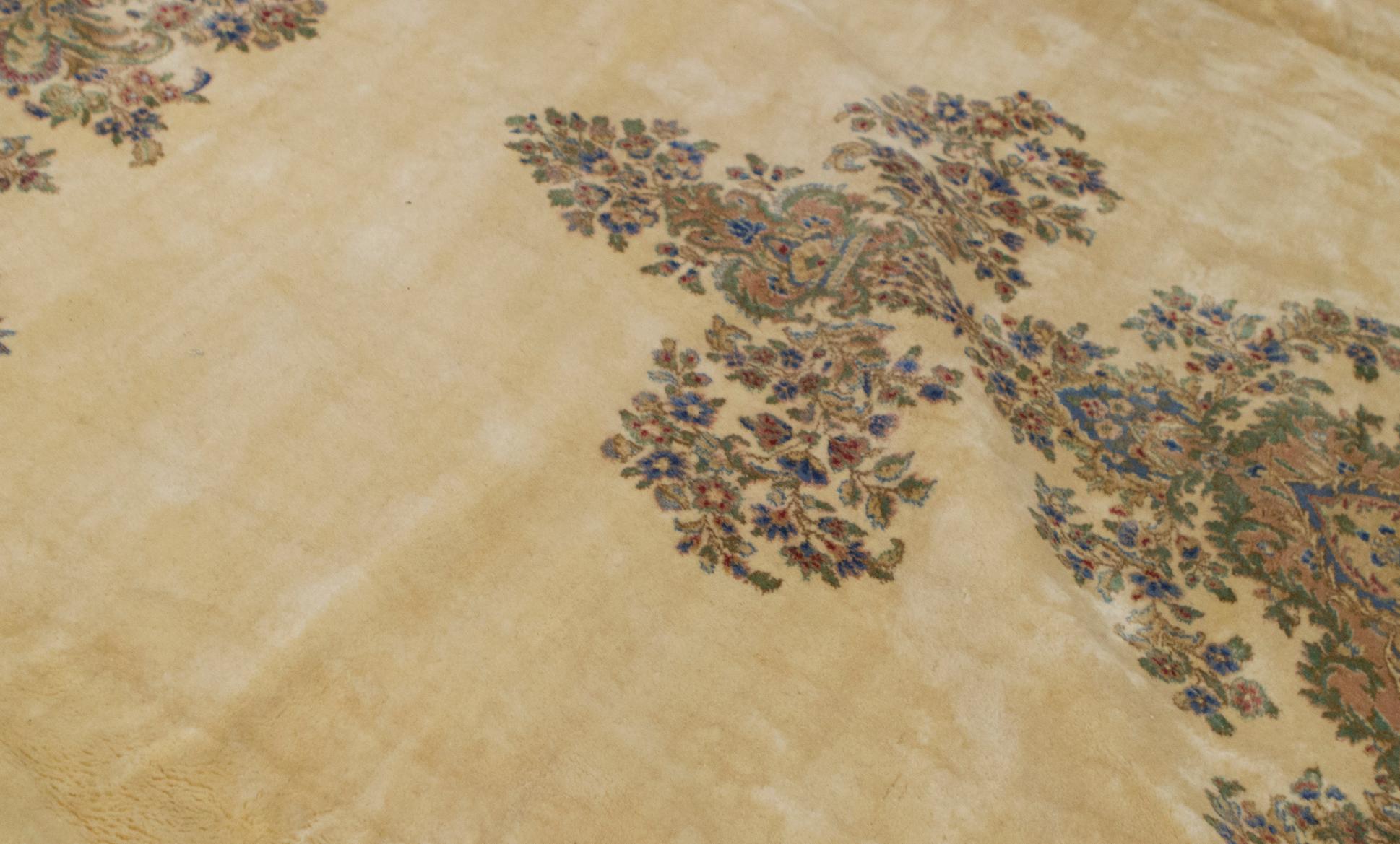 A delightful Kerman rug woven with exquisite detail, the red ground filled with weaving floral designs surrounding a central ivory and soft blue medallion bounded by a soft green main border and ivory and blue guard borders to give this rug a
