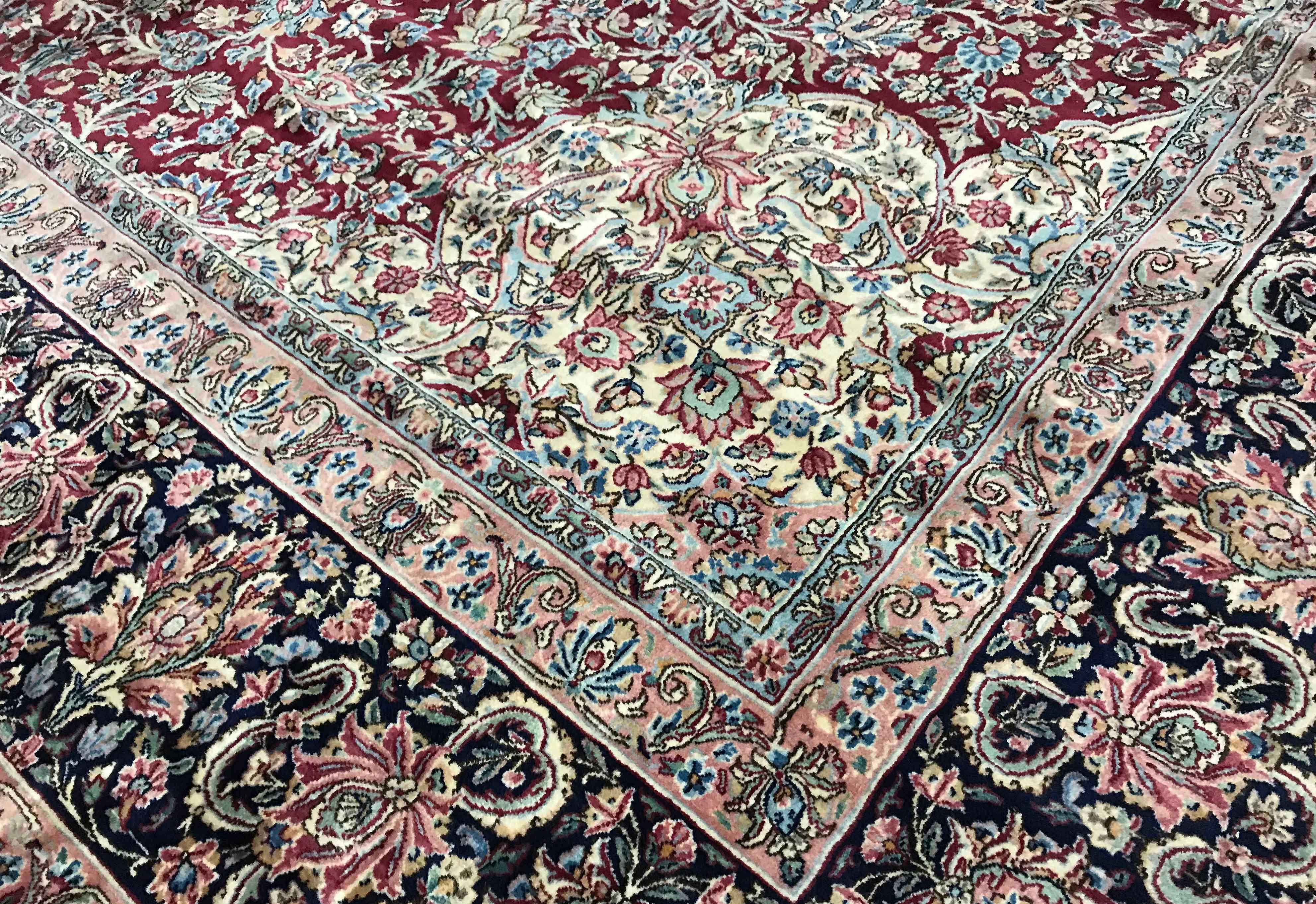 Vintage Persian Kirman, circa 1940. Set on a red ground with a deep navy central design this lovely Kerman has all the requirements one is looking for in a traditional Persian rug. Completed by the main border in dark navy to set the piece off.