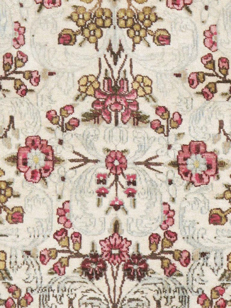 A vintage Persian Lavar Kerman rug from the mid-20th century. Flowers grow up the field and in from the borders on this ivory ground totally lyrical runner. Lightly drawn acanthus fronds add to the garden effect. The floral clusters of the main