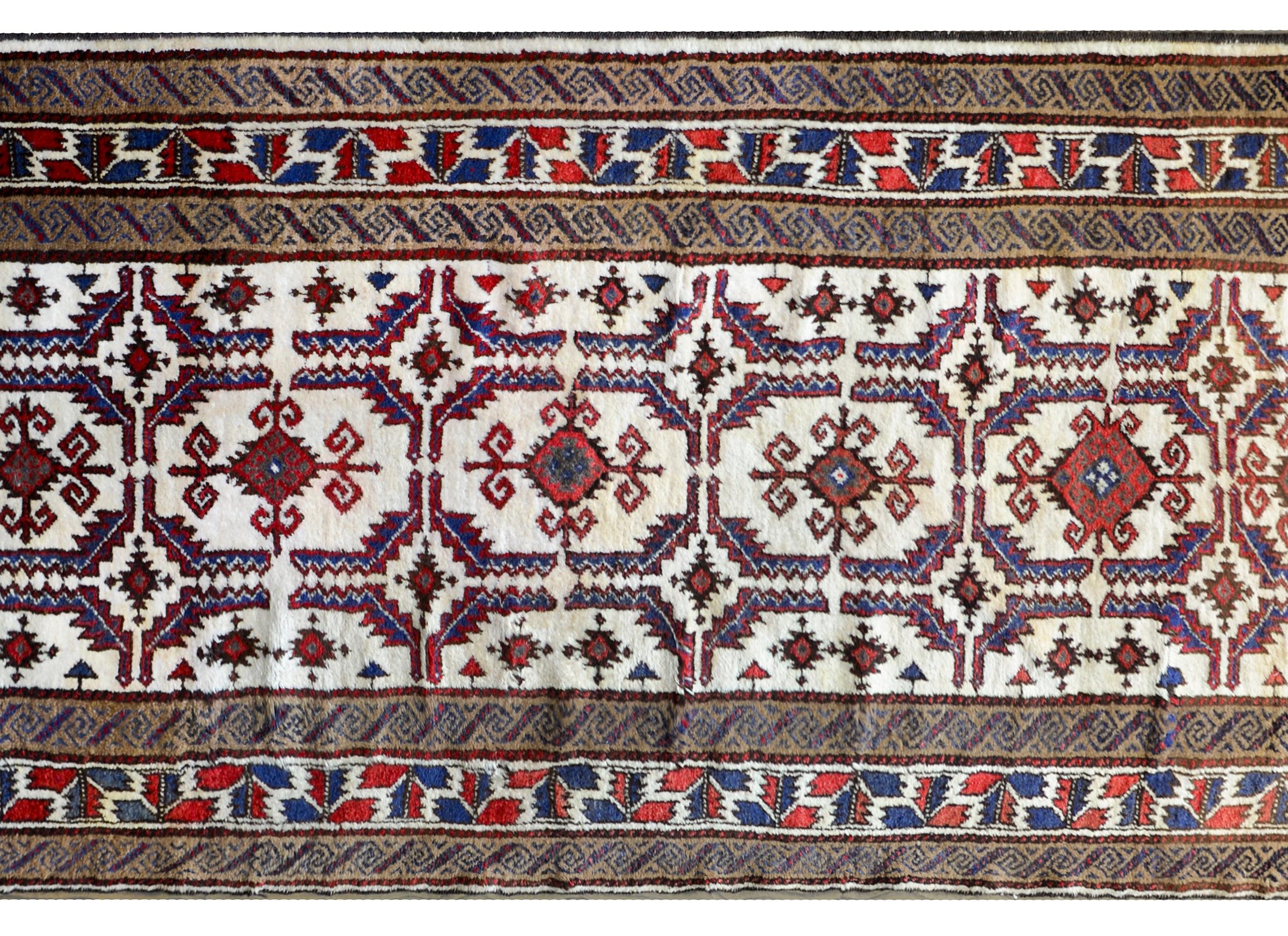 A beautiful vintage Persian Lori runner with a wonderful stylized floral pattern woven in crimson, indigo, and brown against a natural undyed wool background. The border is fantastic composed with three bold geometric tribal patterns woven in