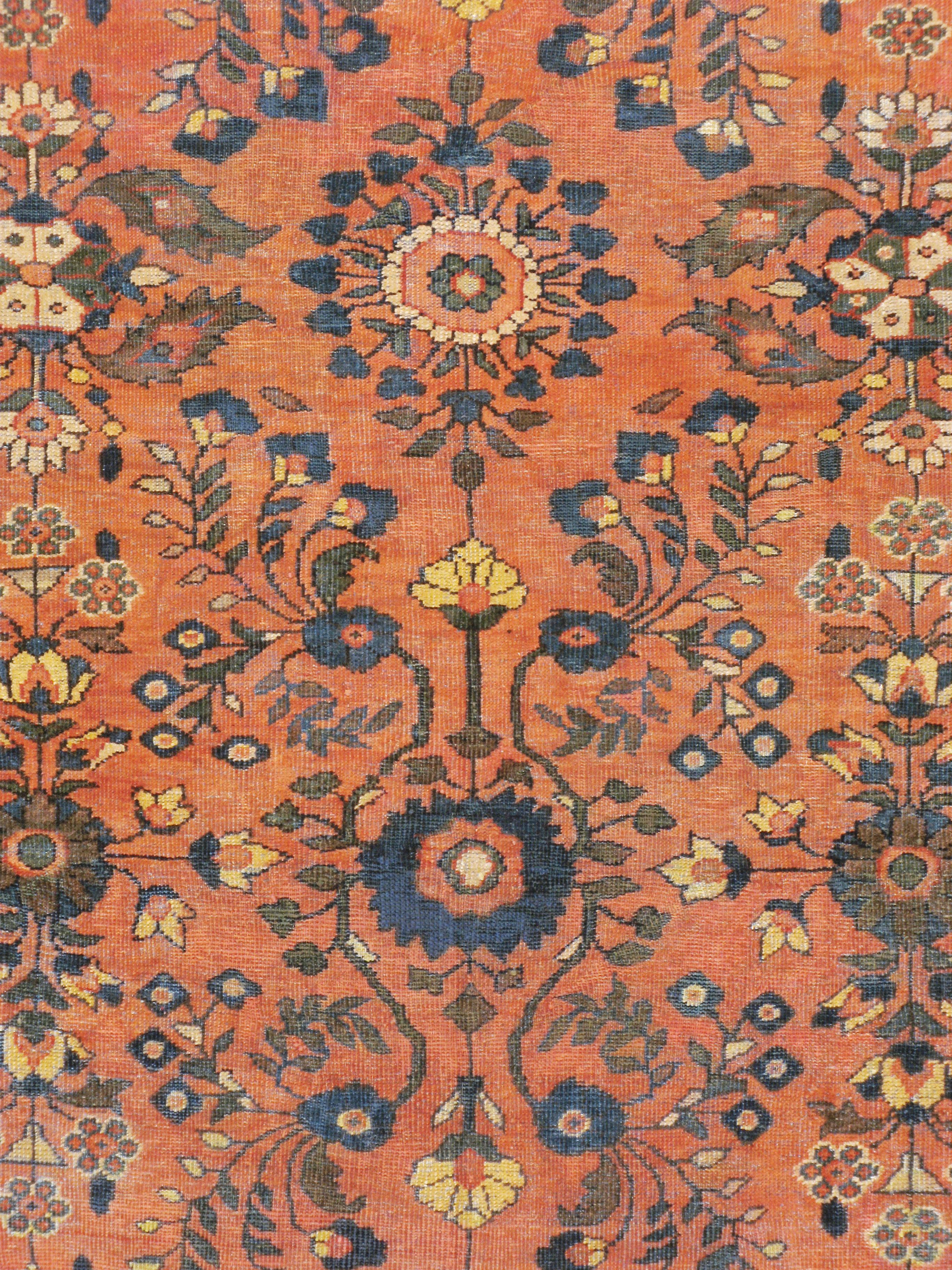 A vintage Persian Mahal carpet from the mid-20th century with an orange field behind a semi-geometric floral pattern in blue and khaki-green often seen on Persian Lilihan carpets. The black border is filled by an overhead view of large floral