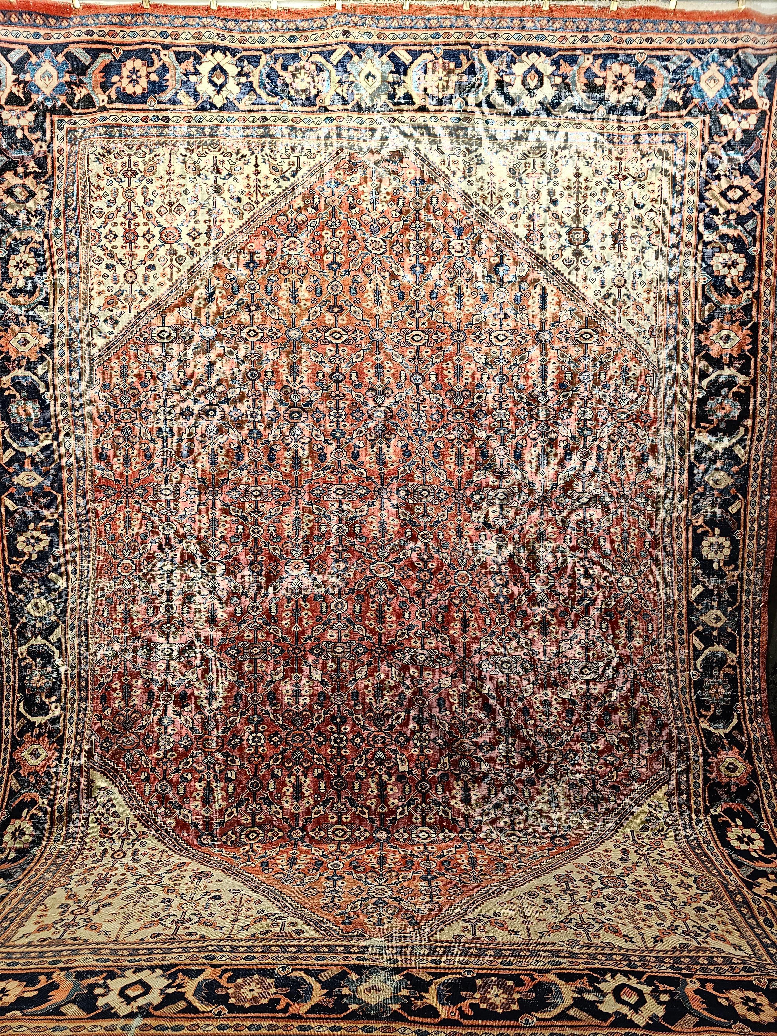 The Persian Mahal/Sultanabad room size carpet from the late 1800s comes in the very desirable all-over design pattern. The field is a brick red color with geometric designs throughout.  The corner spandrels are in ivory or pale yellow which adds to