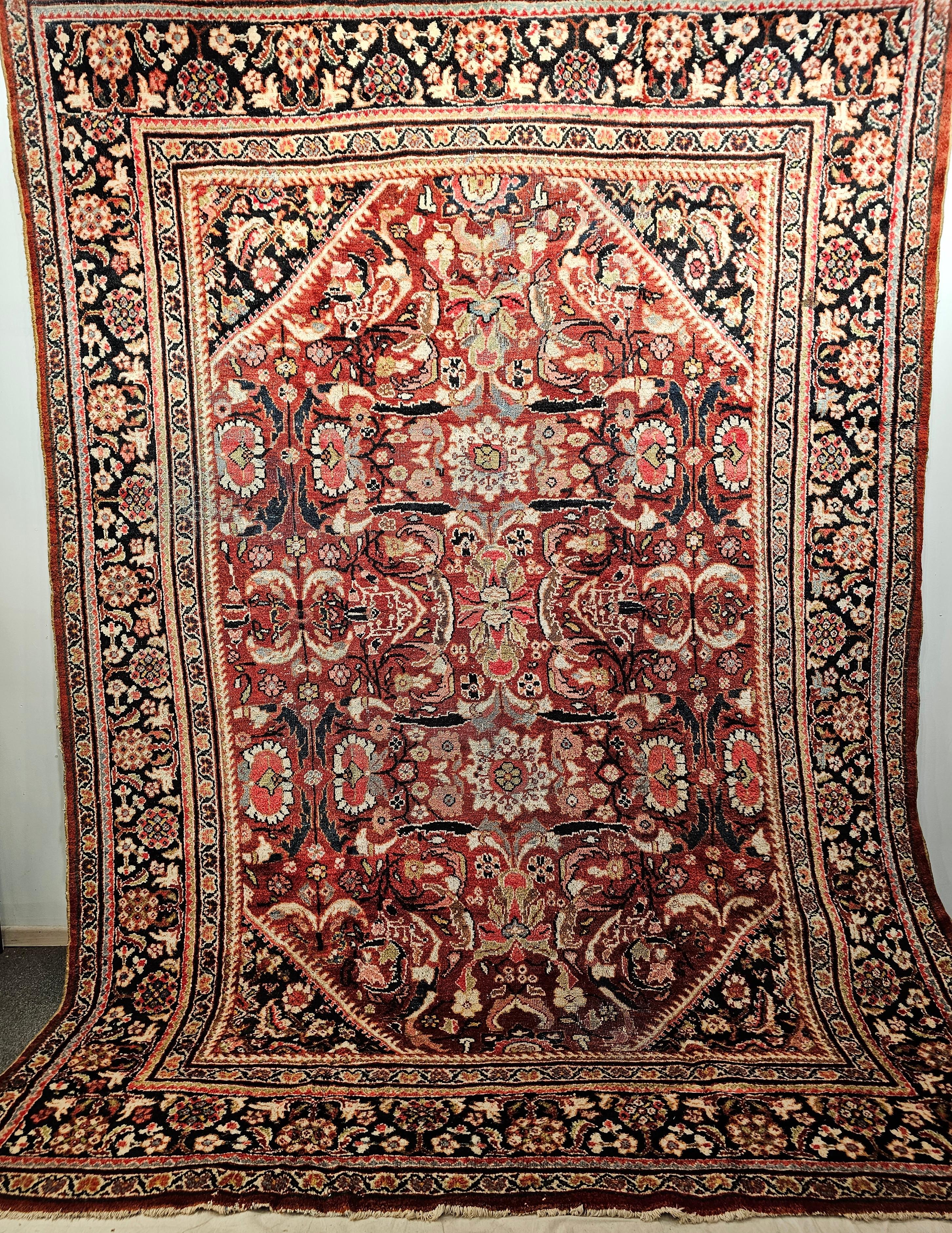 The beautiful and colorful Mahal Sultanabad room-size rug from the early 1900a has an all-over large format pattern in auburn red, navy blue, pink, chartreuse green, and cream colors.  The main field's dark auburn color is a very pleasing and ideal