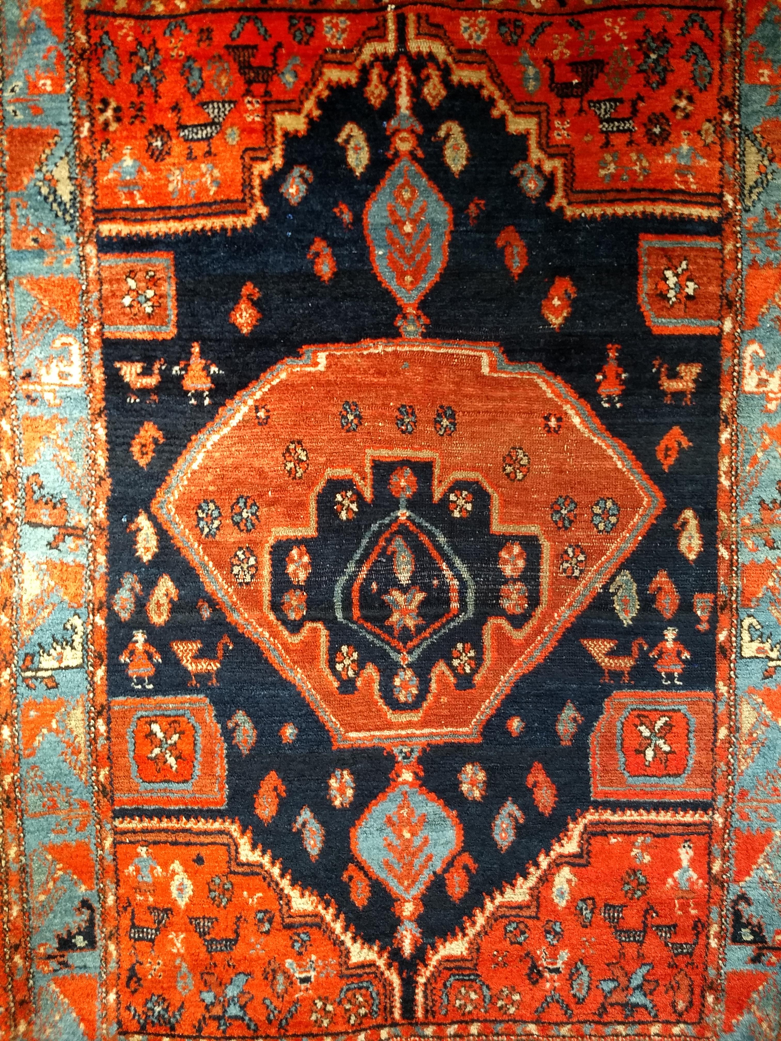 A beautiful Persian Mission Malayer area rug with a truly unique medallion design in navy blue, turquoise, and terracotta colors from the early 1900s.   A great example of village weaving with the design of human and animal forms throughout.  The