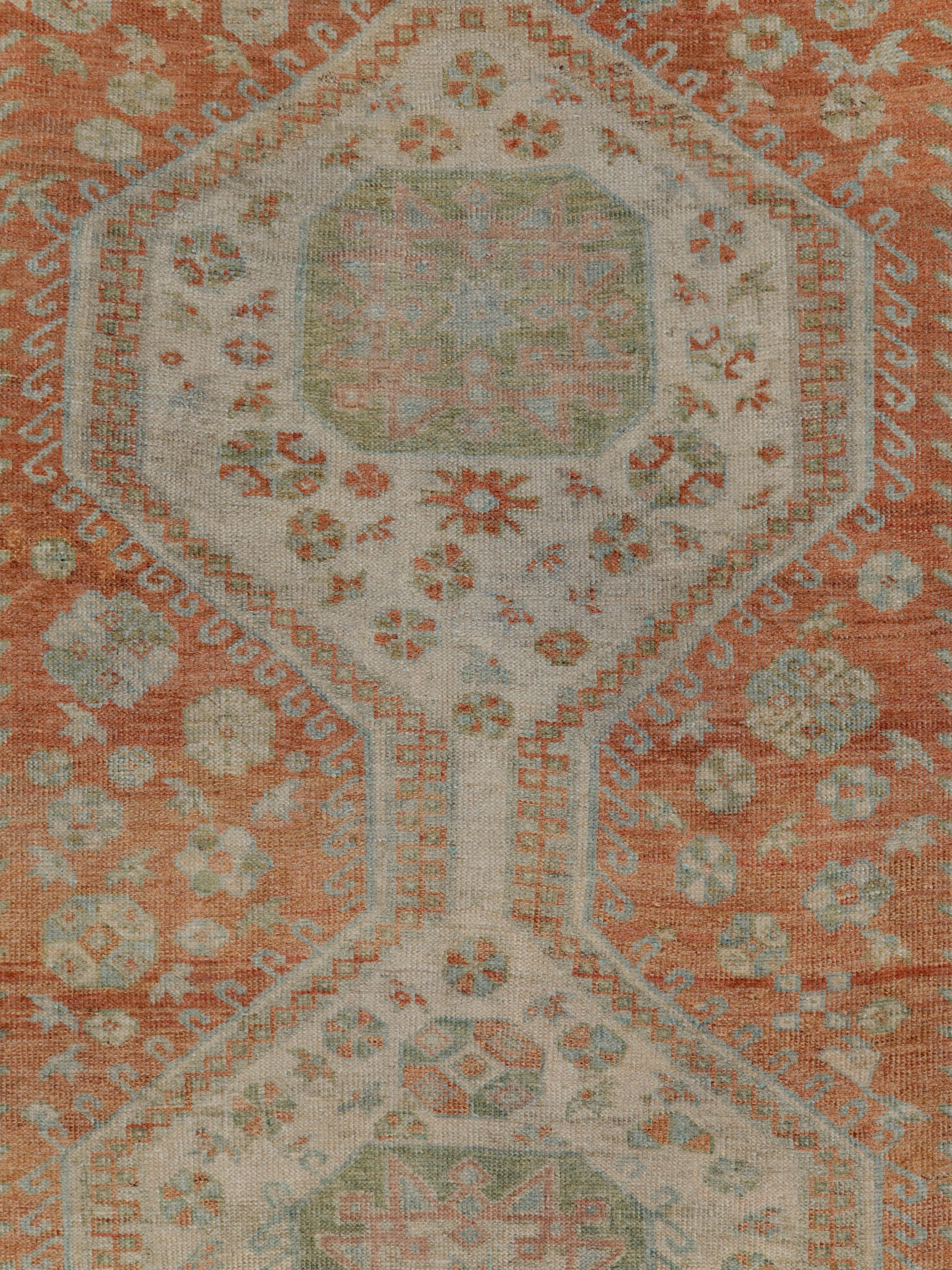 A vintage Persian Malayer rug from the mid-20th century with a pole design consisting of 3 geometric medallions outlined by a fish hook pattern in the centre and 2 elongated plants to the left and right. The terracotta field adds a delicate contrast