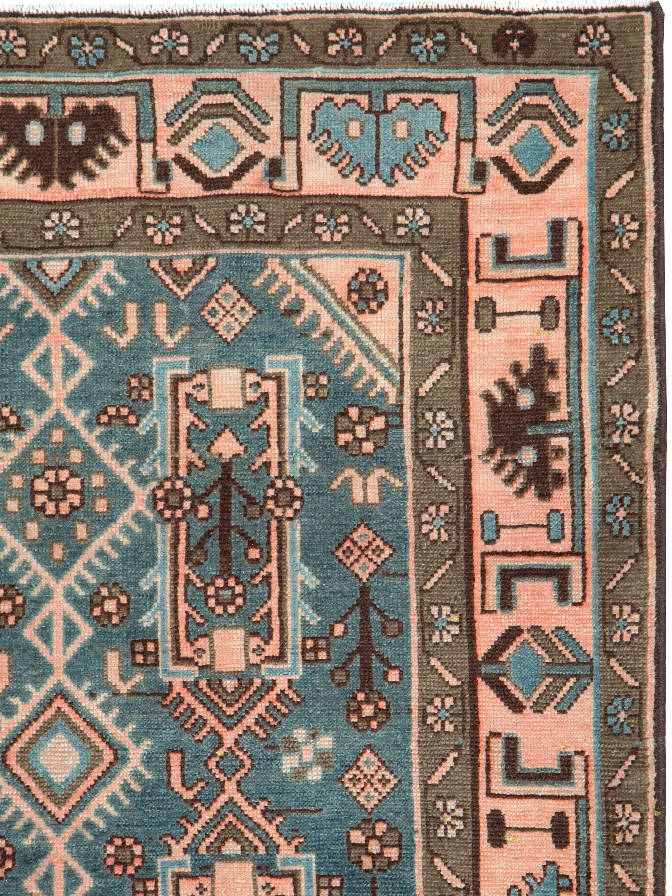 A vintage Persian Malayer carpet from the mid-20th century with a blue-green field and detailed in New York pink, and a border utilizing the same shades.