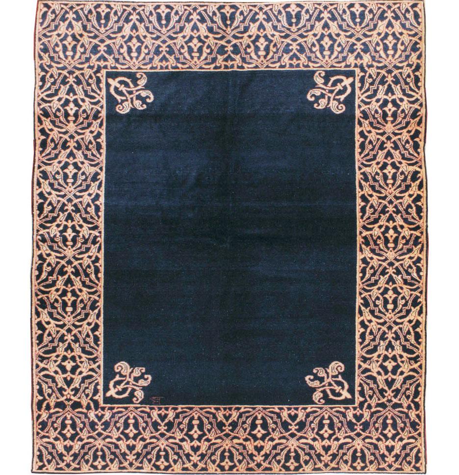 A vintage Persian Malayer area rug handmade during the mid-20th century with a solid navy blue colored field and an intricate Art Deco style arabesque border. The design is very versatile and works well with both European Renaissance traditional