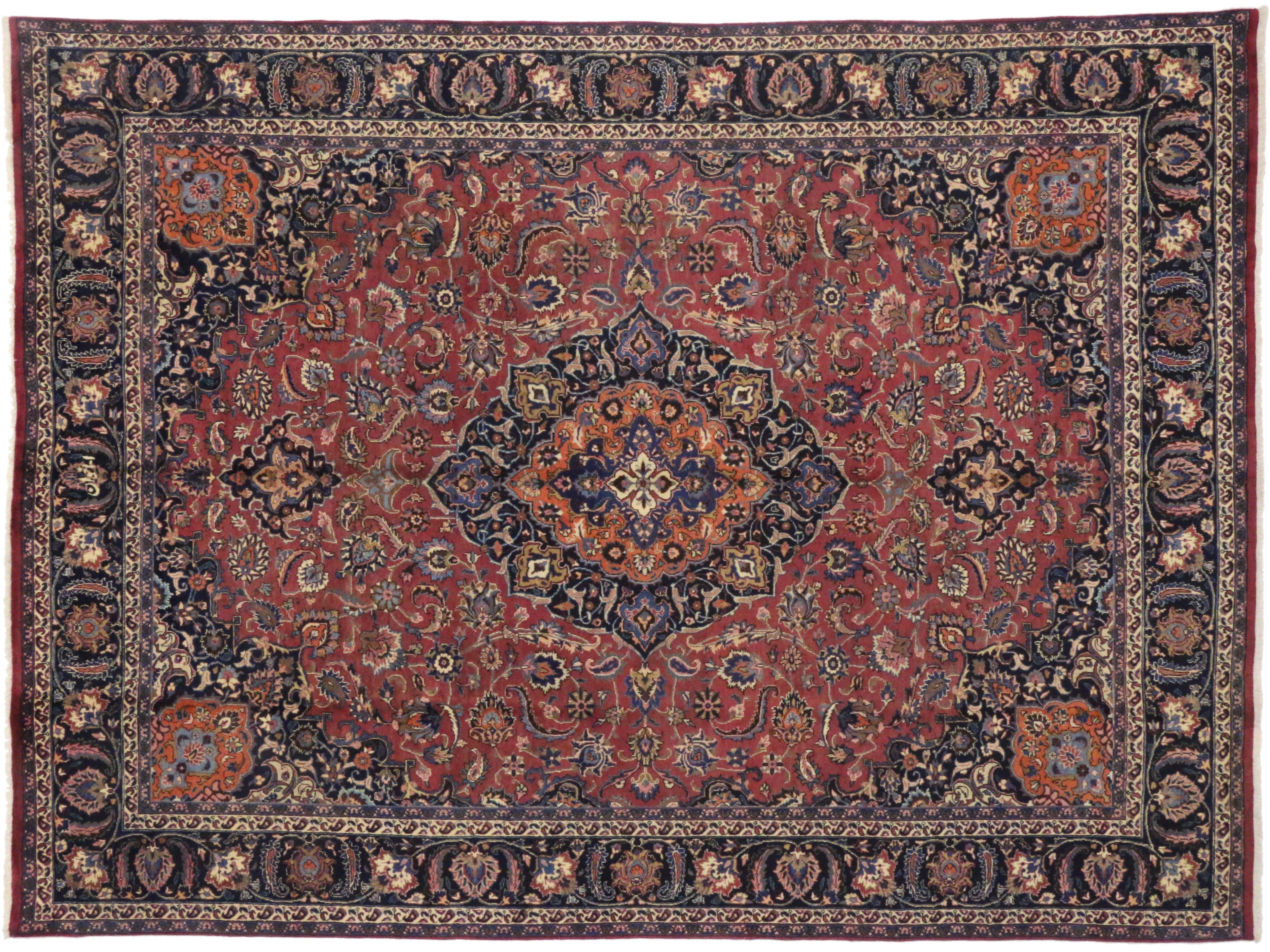 Characterizing the lavish curvilinear style of Art Nouveau, this vintage Persian Mashhad rug features an ornate centre medallion surrounded by an all-over floral pattern and arabesque spandrels. The meandering botanical motifs and ornate floral
