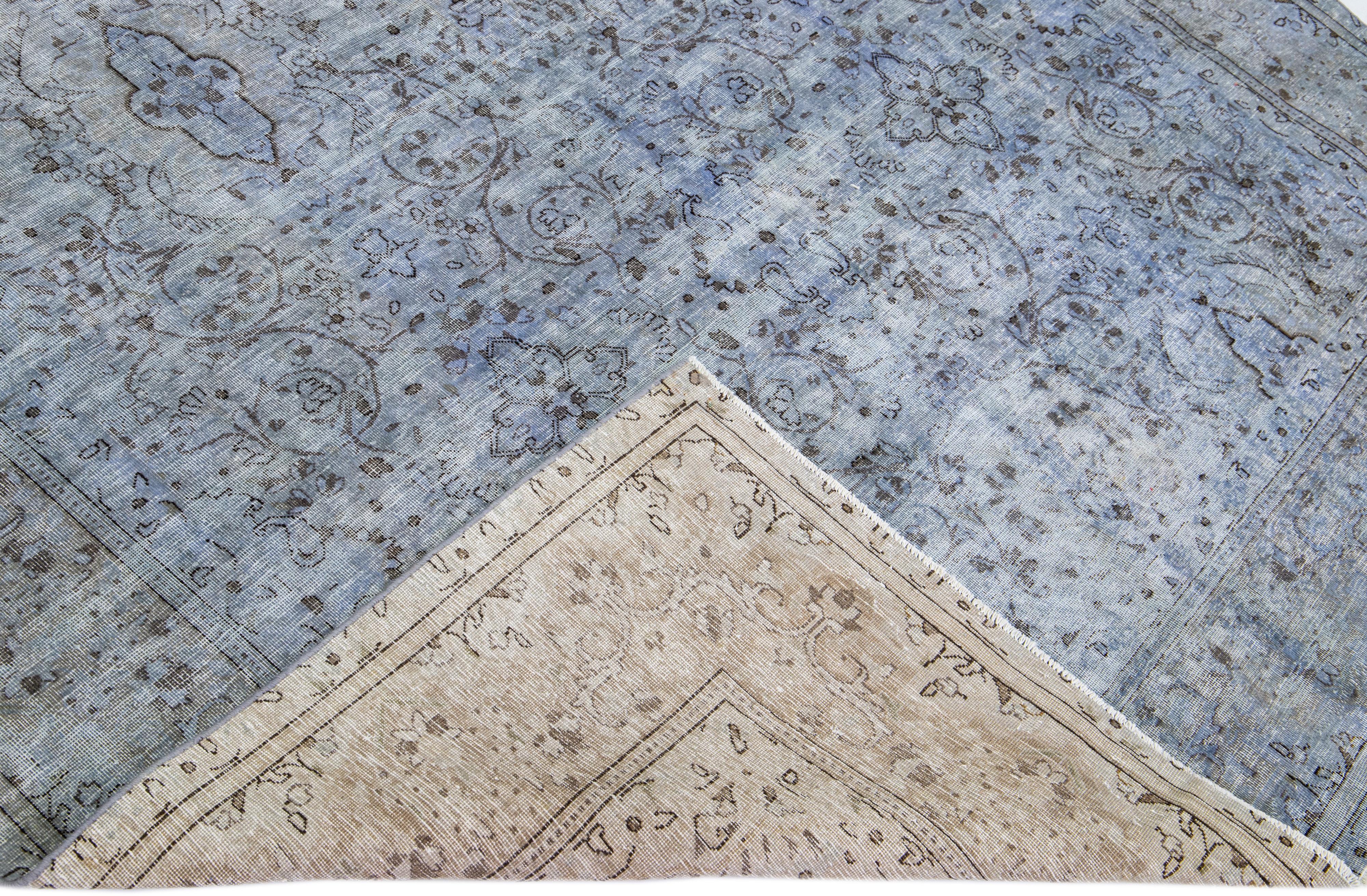 Magnifique tapis vintage en laine surteinte nouée à la main avec un champ bleu. Ce tapis persan présente un motif floral sur toute sa surface.

Ce tapis mesure : 6'8'' x 9'4