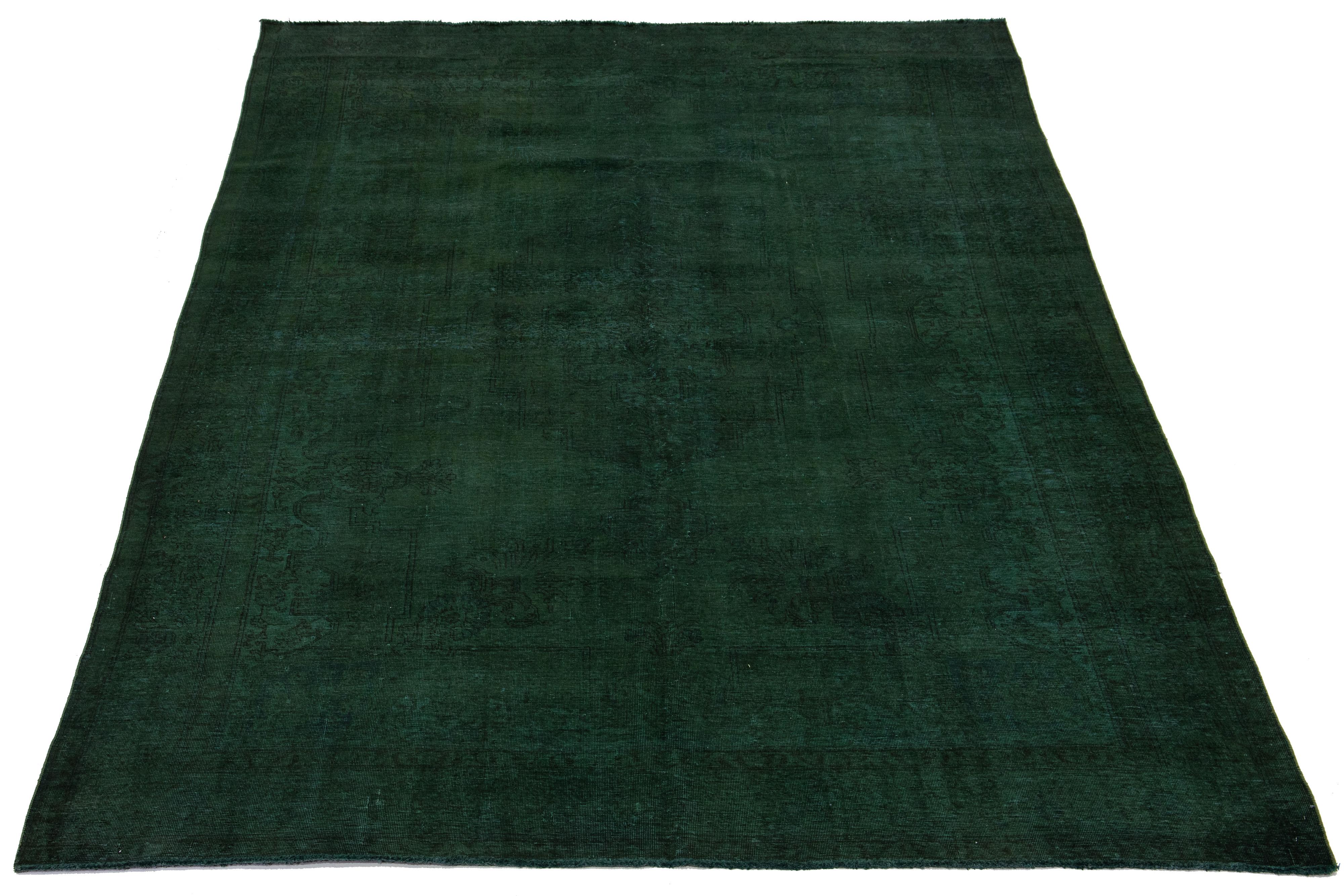  This is a vintage Persian rug made of hand-knotted wool with a green field. The rug has a medallion floral design with brown accents. 

This rug measures 9'11'' x 15'7