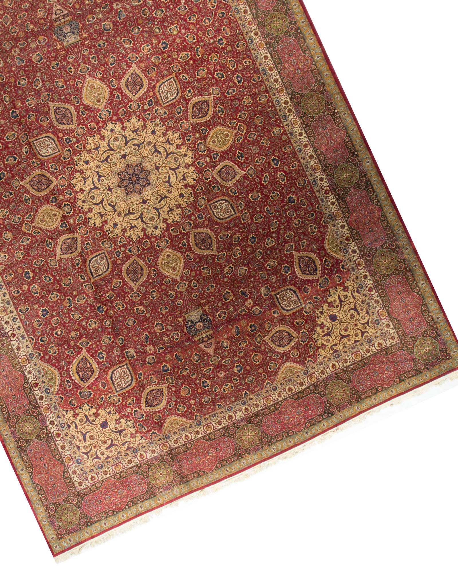 Vintage Persian oversize Tabriz rug, circa 1920. This wonderful rug has a central medallion surrounded by a serrated leaf pattern on a red ground that gives the feel of the sun bursting thru. The soft rose border helps to give the rug a light and