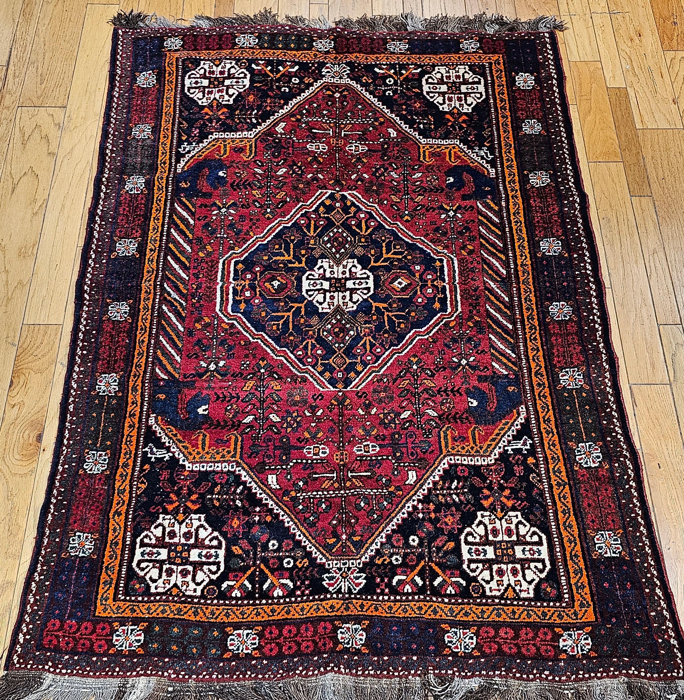 Vintage Persian Qashqai (Ghashghai) tapis tribal du sud-ouest de la Perse vers le milieu des années 1900.   Le tapis Qashqai présente un format de design tribal traditionnel qui comprend un médaillon central et quatre petits médaillons dans les