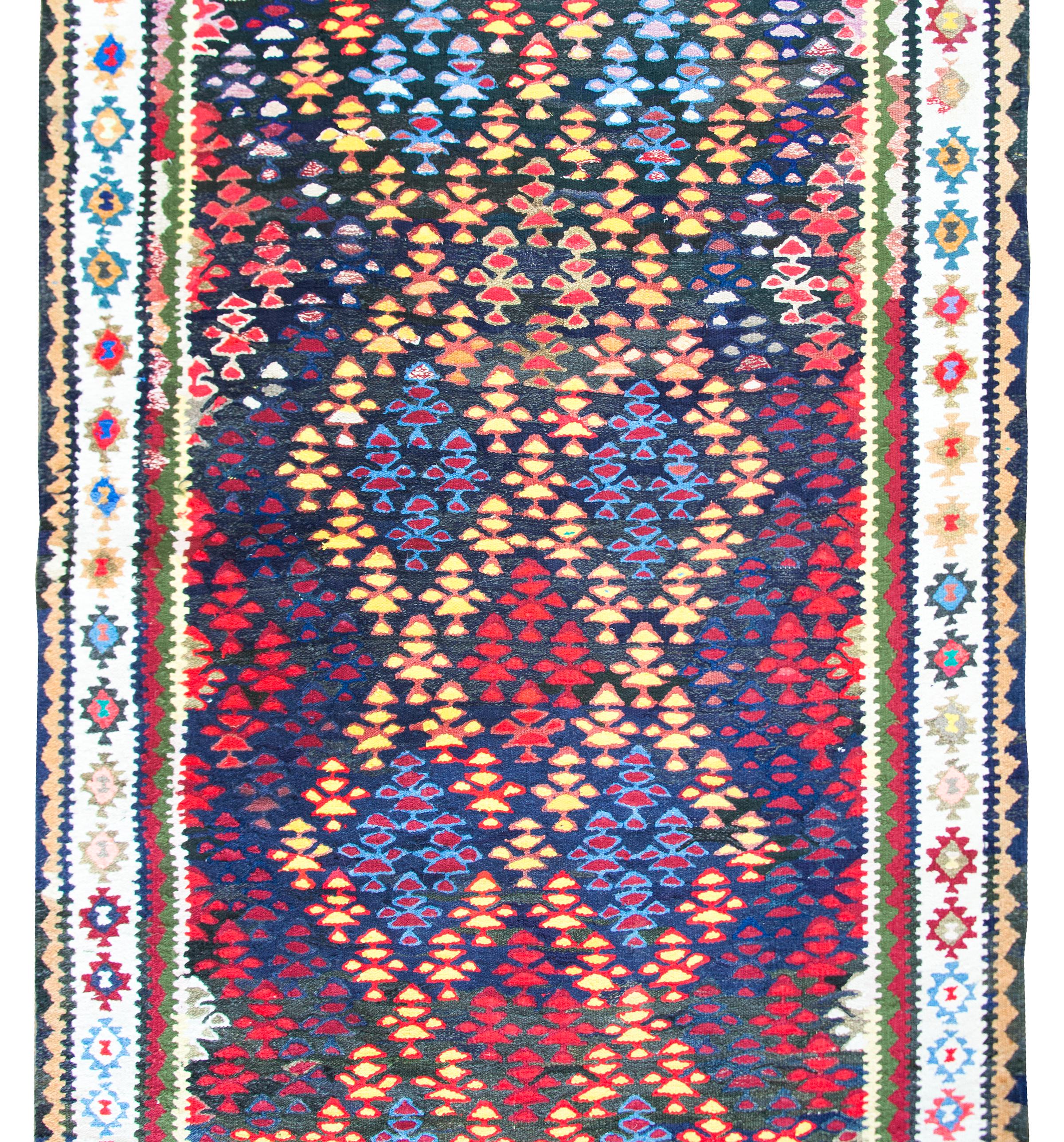 Magnifique tapis kilim persan vintage avec des arbres de vie multicolores tissés dans un motif de bandes entrecroisées créant des losanges et un motif de treillis, entouré d'une bordure complexe de fleurs plus stylisées et de motifs géométriques, le