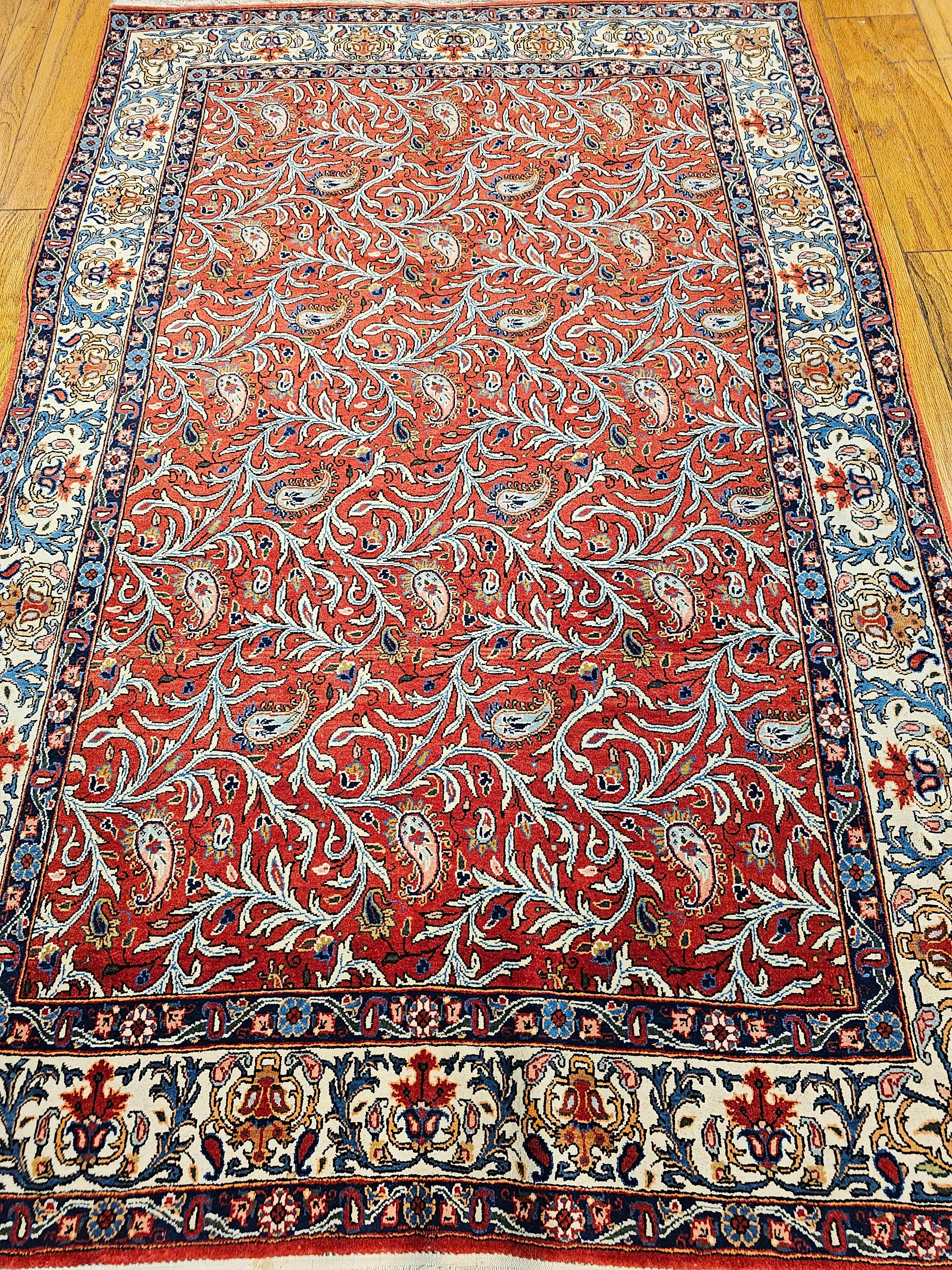 A vintage Persian Qum in an all over paisleys and meandering vines pattern set on a rich red background from the second quarter of the 1900s.  The rug has an allover design of wavering vines and paisley forms set in a rich red color field.   The
