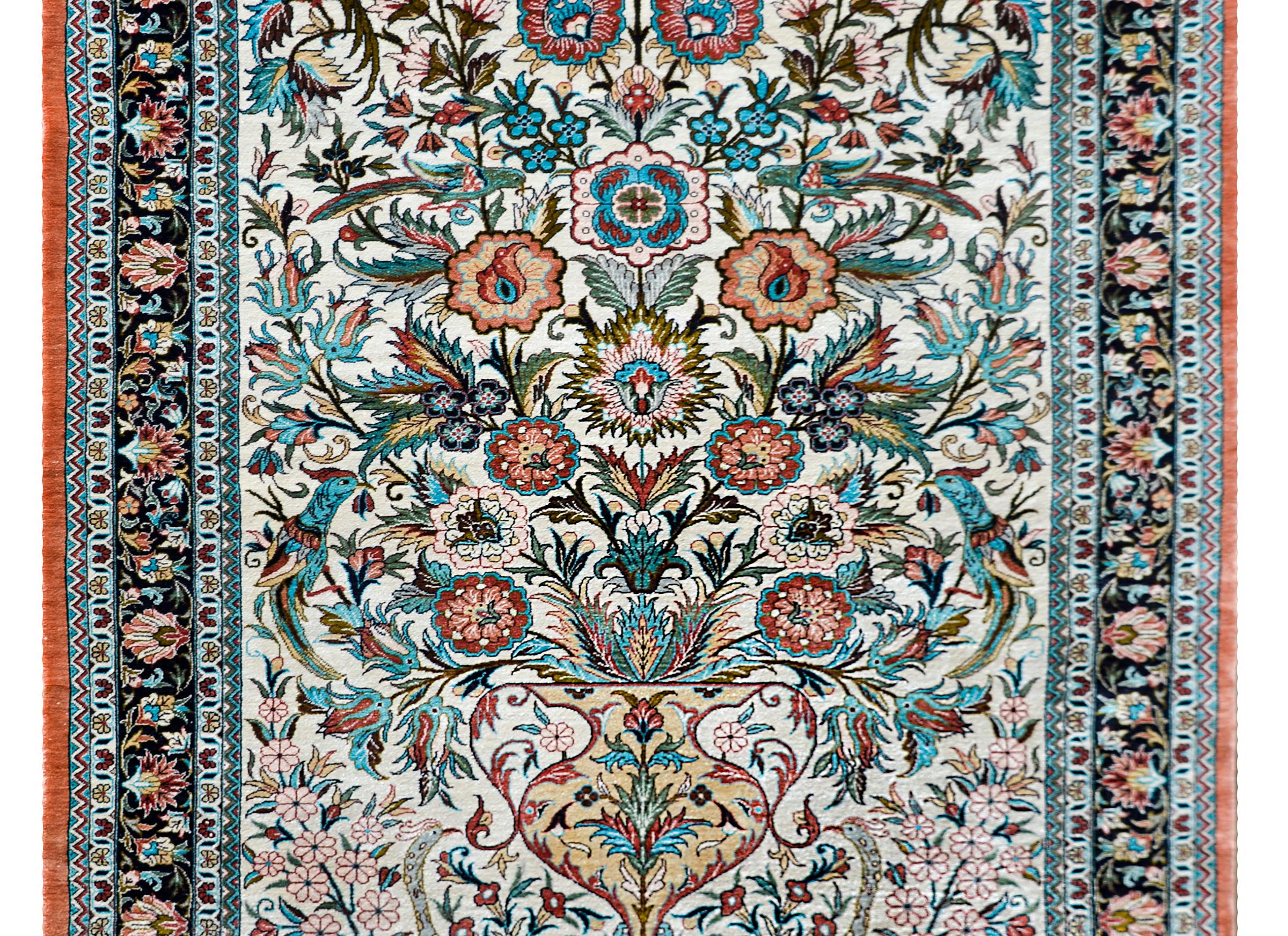 A fantastic vintage Persian Qum silk rug with an incredible tree-of-life pattern with large-scale flowers rendered in beautiful reds, indigos, greens, golds, and pinks, and surrounded by several birds. The border is complex designed with multiple