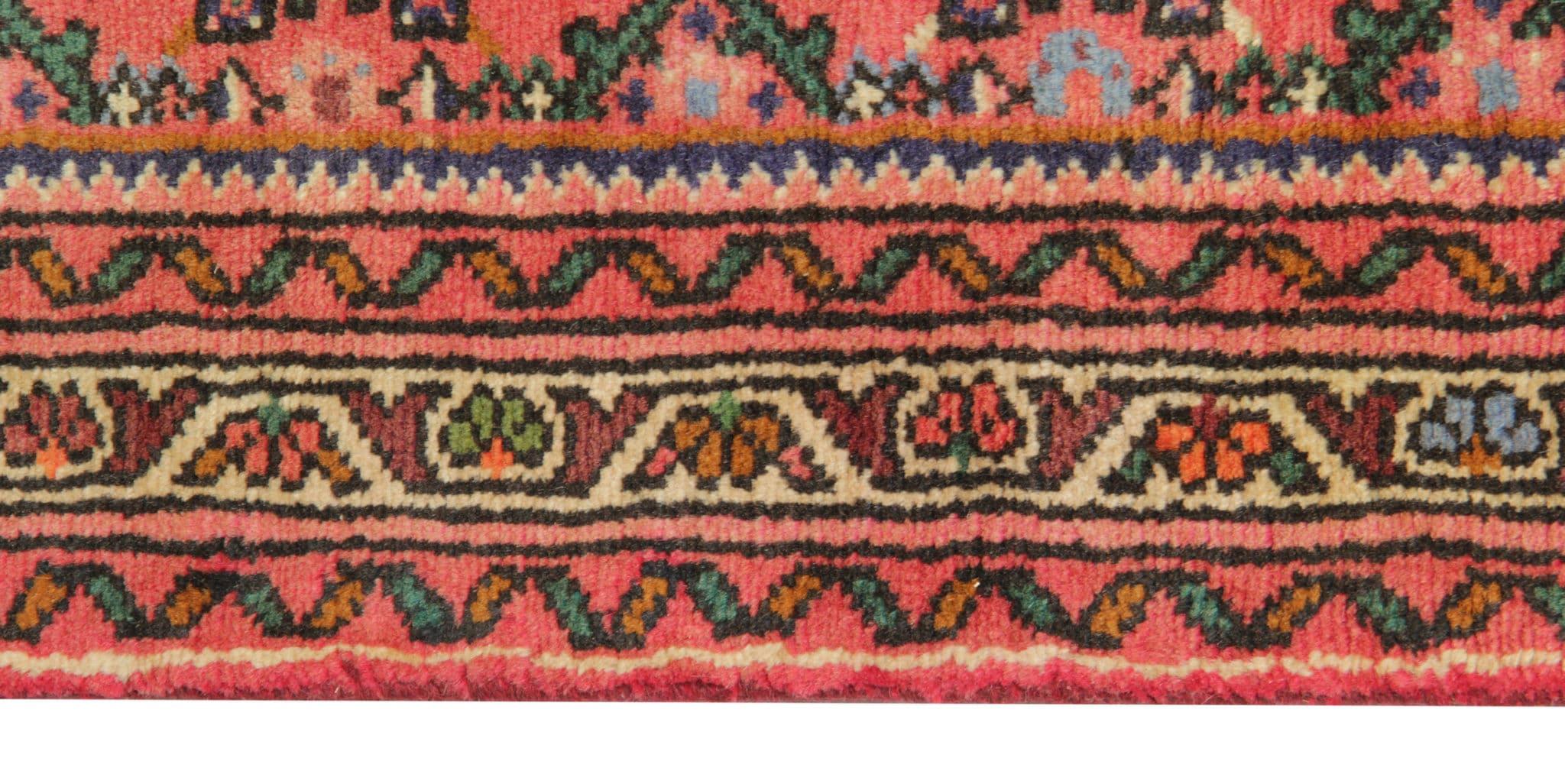 This vintage geometric runner rug in rust pink is hand-knotted with care. This exquisite piece boasts a blend of wool and cotton, ensuring both durability and softness underfoot. Crafted in the 1950s, it carries a timeless charm, with its