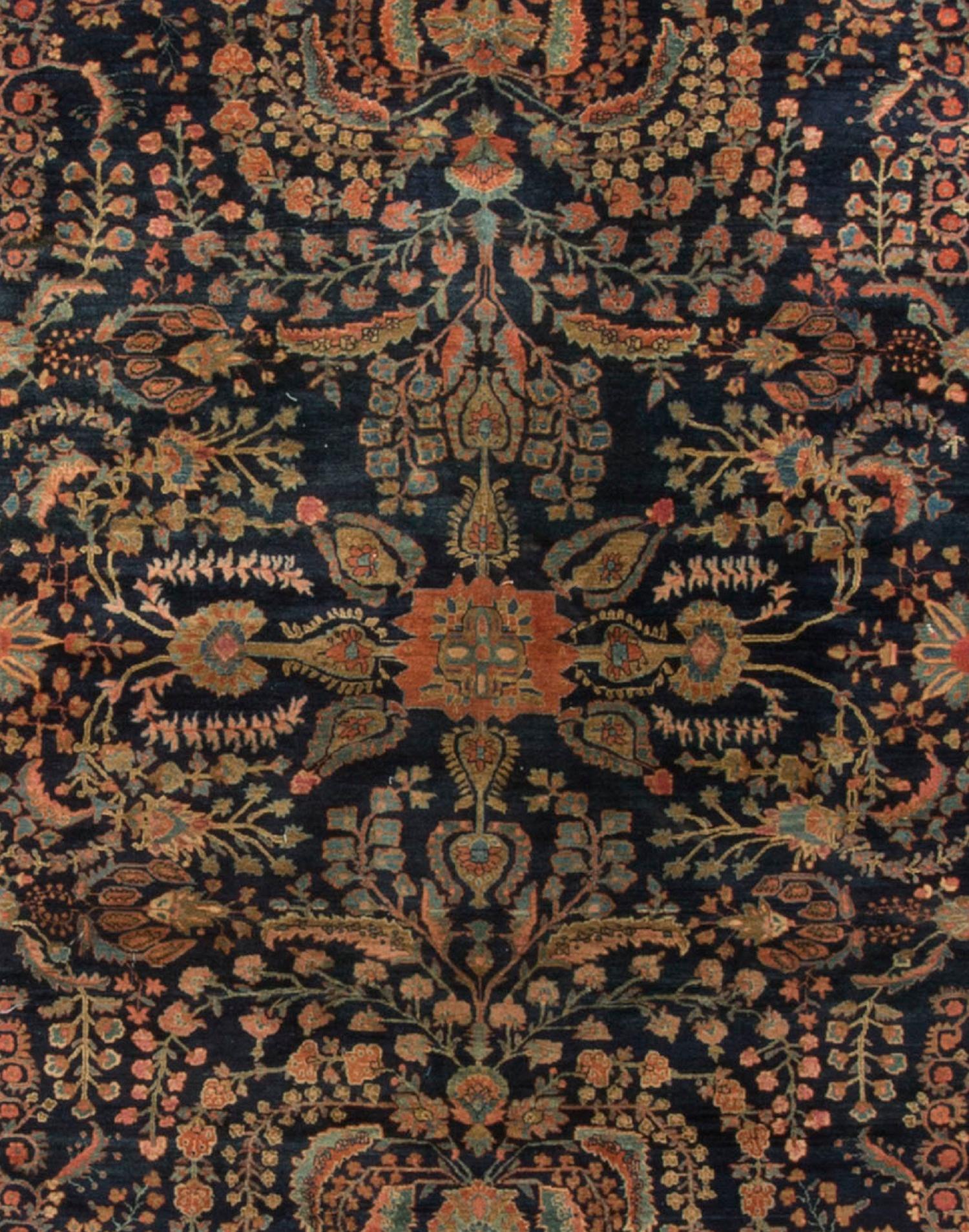 The deep navy field in this antique Persian Sarouk handwoven rug has a marvelous display of flowers sitting at either end of the rug in a pale blue vase. The central floral design adds to the overall look of lightness. The main border and two guard