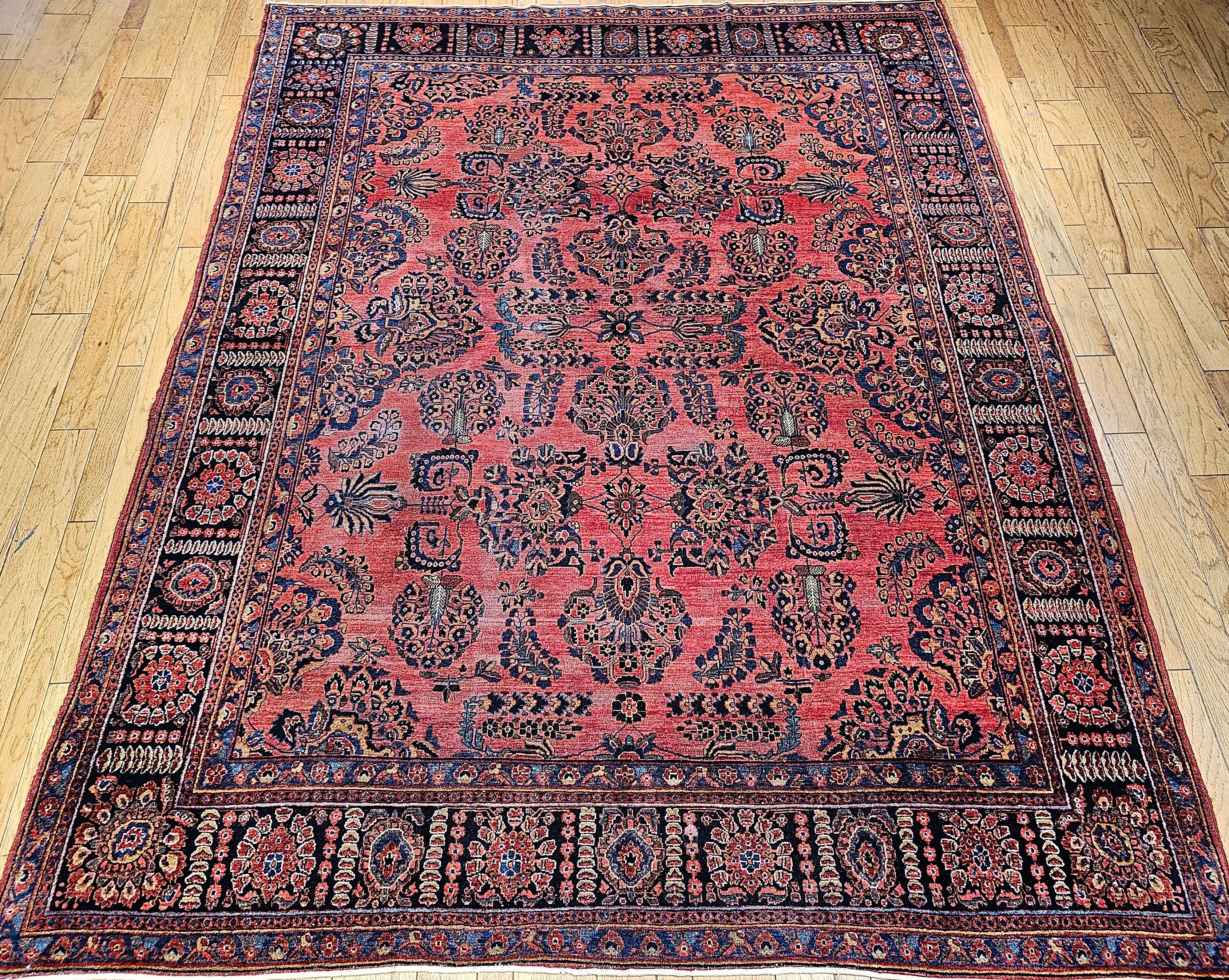 A beautiful hand-knotted Persian Sarouk room size rug from the 1st quarter of the 20th century.  The rug is distinct in having an open and uncluttered allover design field consisting of large flower bouquet forms set on a dark red background.   The