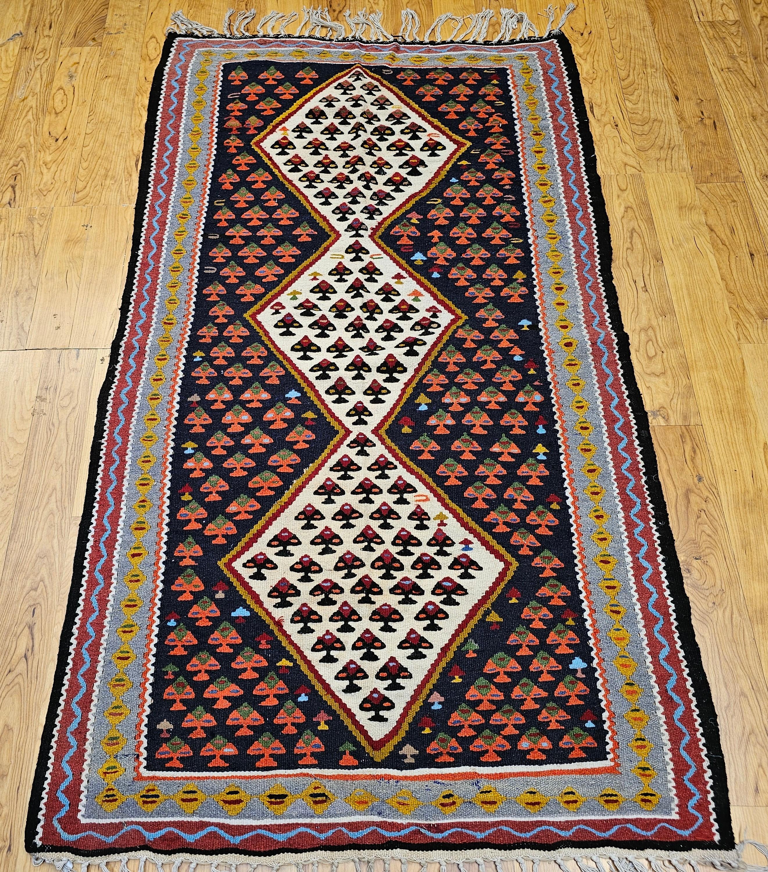 Bellissimo tappeto persiano Senneh kilim vintage proveniente dalla regione curda della Persia occidentale. Il Kilim Senneh ha la forma ripetuta di un piccolo fiore al centro di 3 diamanti bianchi posti in un campo di colore nero con i fiori in