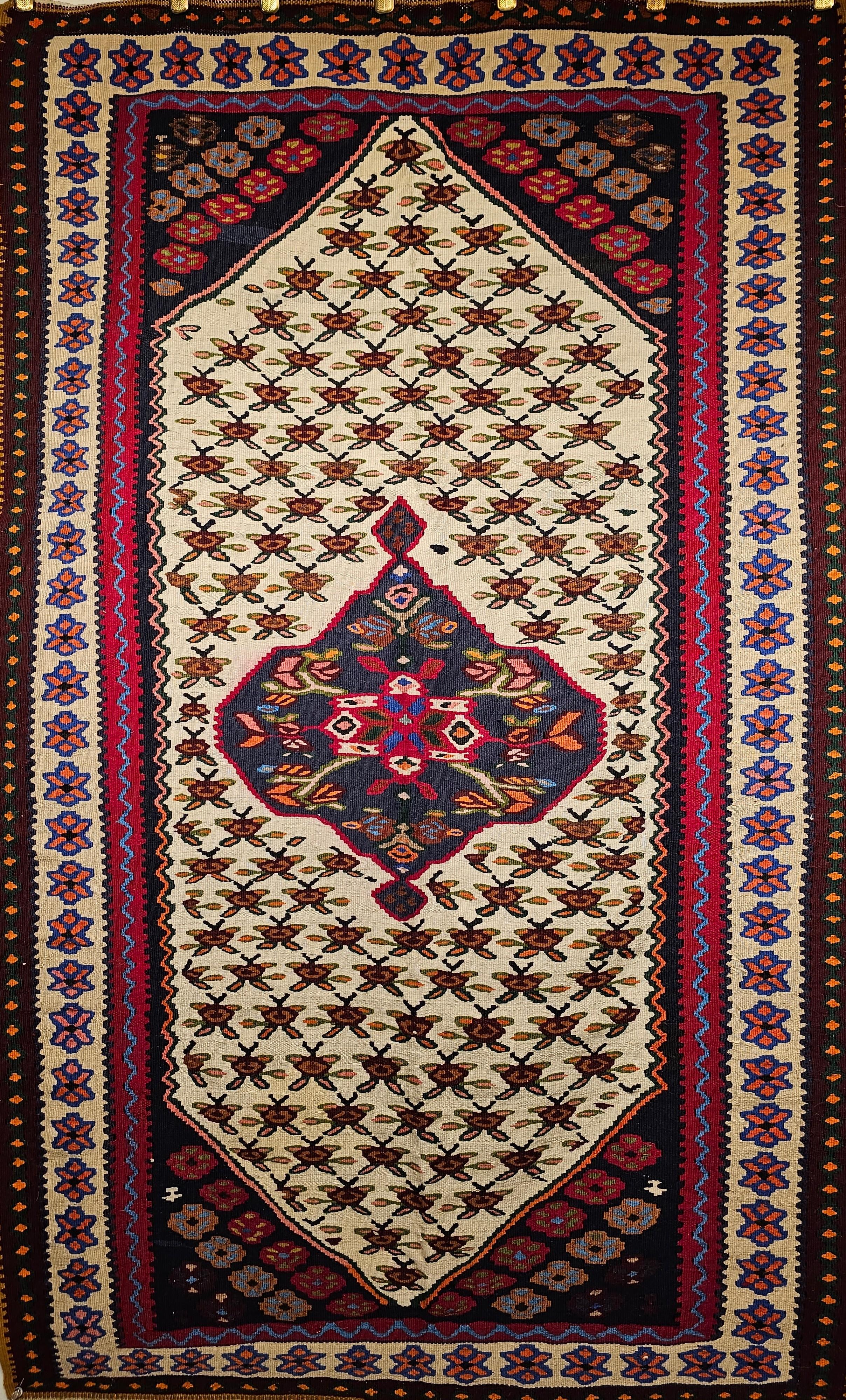 A beautiful vintage Persian Senneh (Bidjar) Kilim area rug from the Kurdistan region of Western Persia. The Senneh kilim comes with a central medallion that has a geometric design in dark blue with designs in red, cream, and yellow.  The medallion