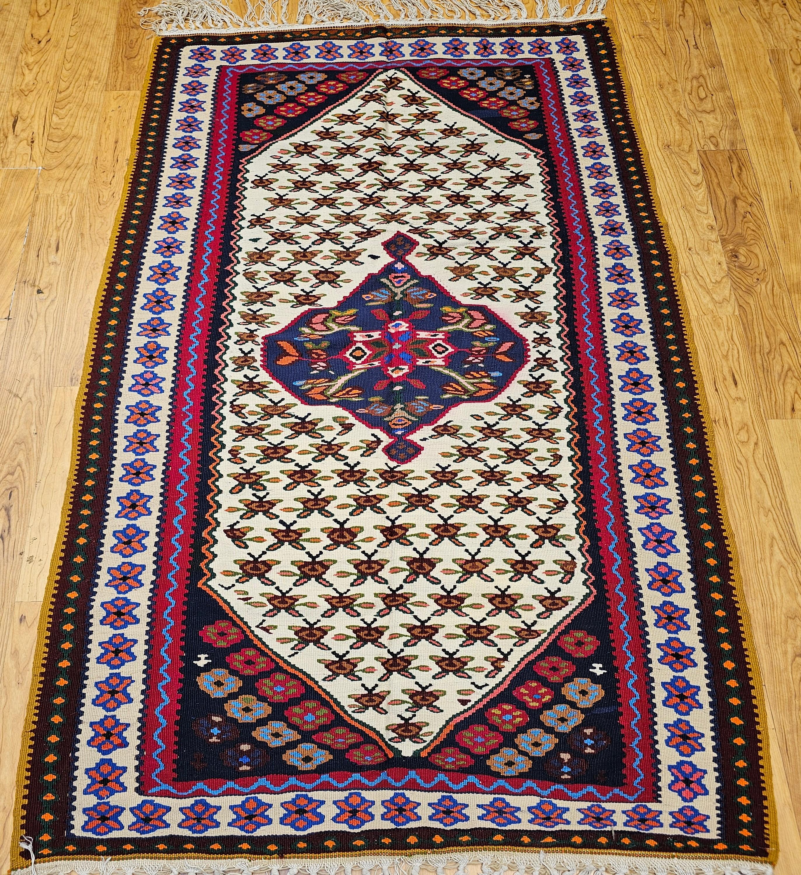 Bellissimo tappeto persiano vintage Senneh (Bidjar) Kilim proveniente dalla regione del Kurdistan, nella Persia occidentale. Il kilim Senneh presenta un medaglione centrale con un disegno geometrico in blu scuro e disegni in rosso, crema e giallo. 