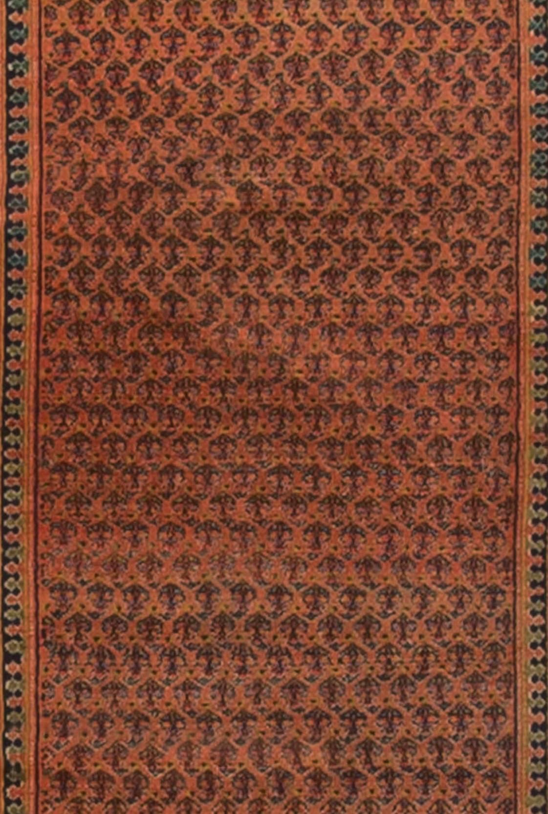 Chemin de table persan vintage tissé à la main, vers 1920. Le champ principal est rempli à ras bord d'un motif paisley sur un fond rouge tendre et entouré de multiples bordures de garde. Dans une couleur foncée sur un dossier plus clair.
 