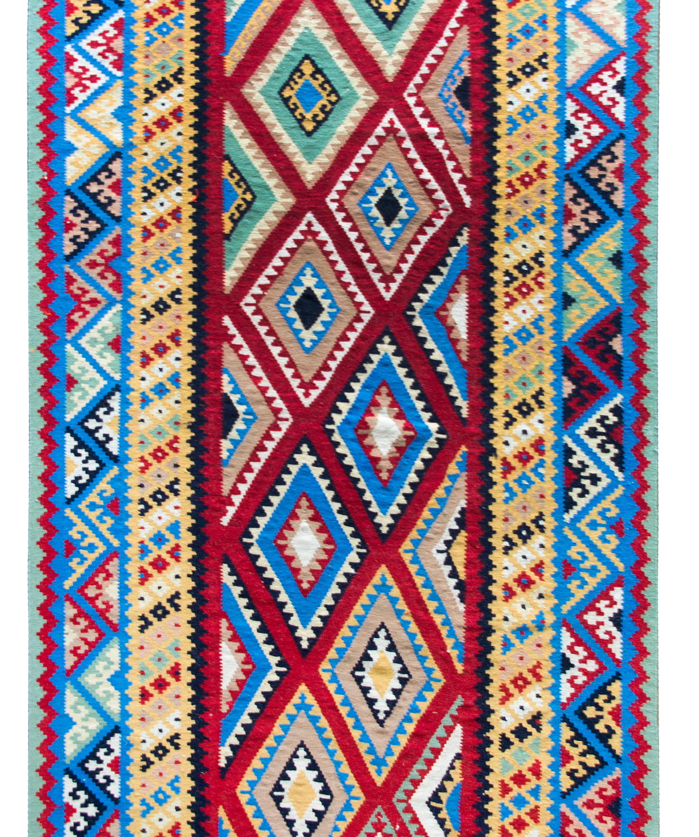 Brillante alfombra persa Shiraz Kilim de época, con un motivo central de rombos rodeado de un elaborado borde geométrico y estilizados motivos florales, todo ello tejido en atrevidos colores que incluyen lanas carmesí, añil, verde, dorado y blanco.
