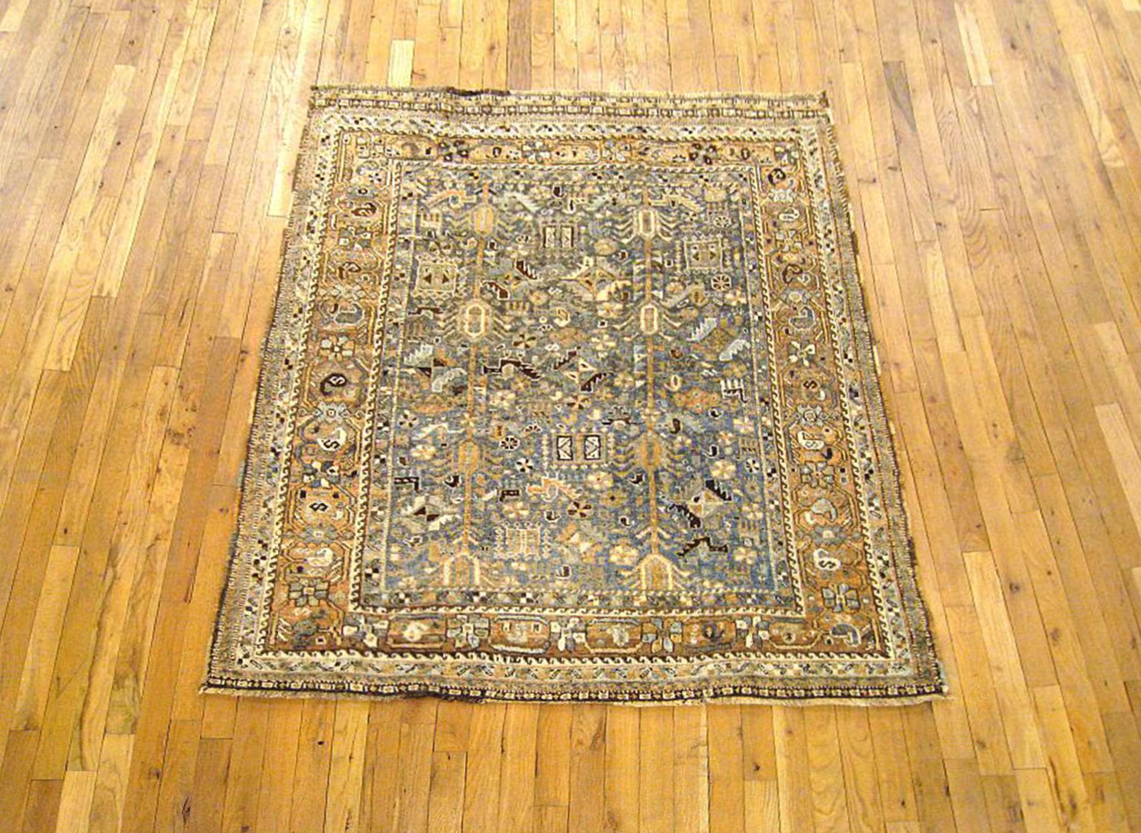 A vintage Persian Shiraz oriental rug, size 5'1 H; x 4'4 W, circa 1940. This lovely small hand-knotted wool carpet features a variety of stylized tribal design elements on the soft blue central field, with a complementary soft red border. The