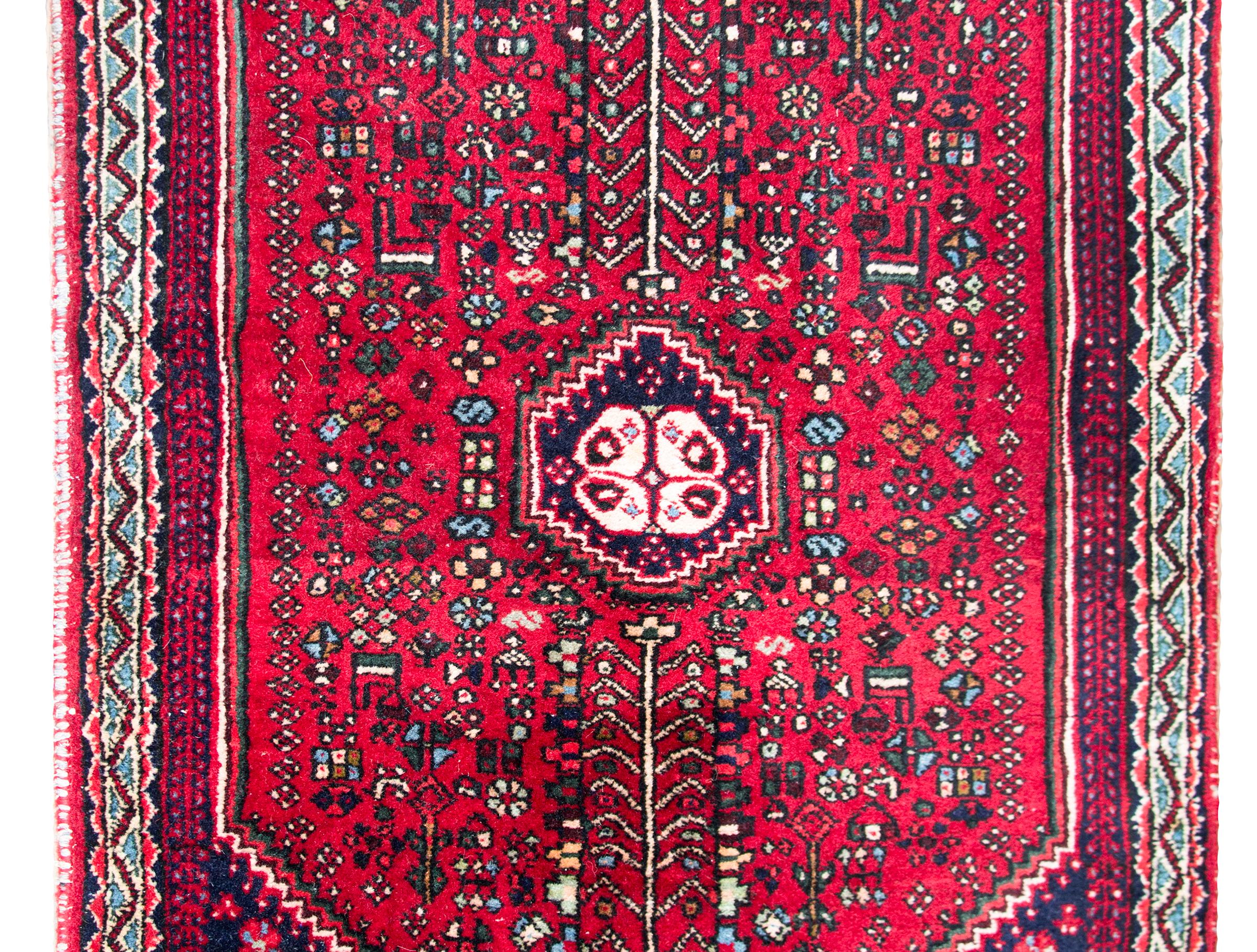 A late 20th century Persian Shiraz rug with a central field filled with myriad stylized flowers surrounded by a field of more flowers, all surrounded by a geometric patterned border, and all woven in brilliant crimsons, indigos, pinks, and creams.