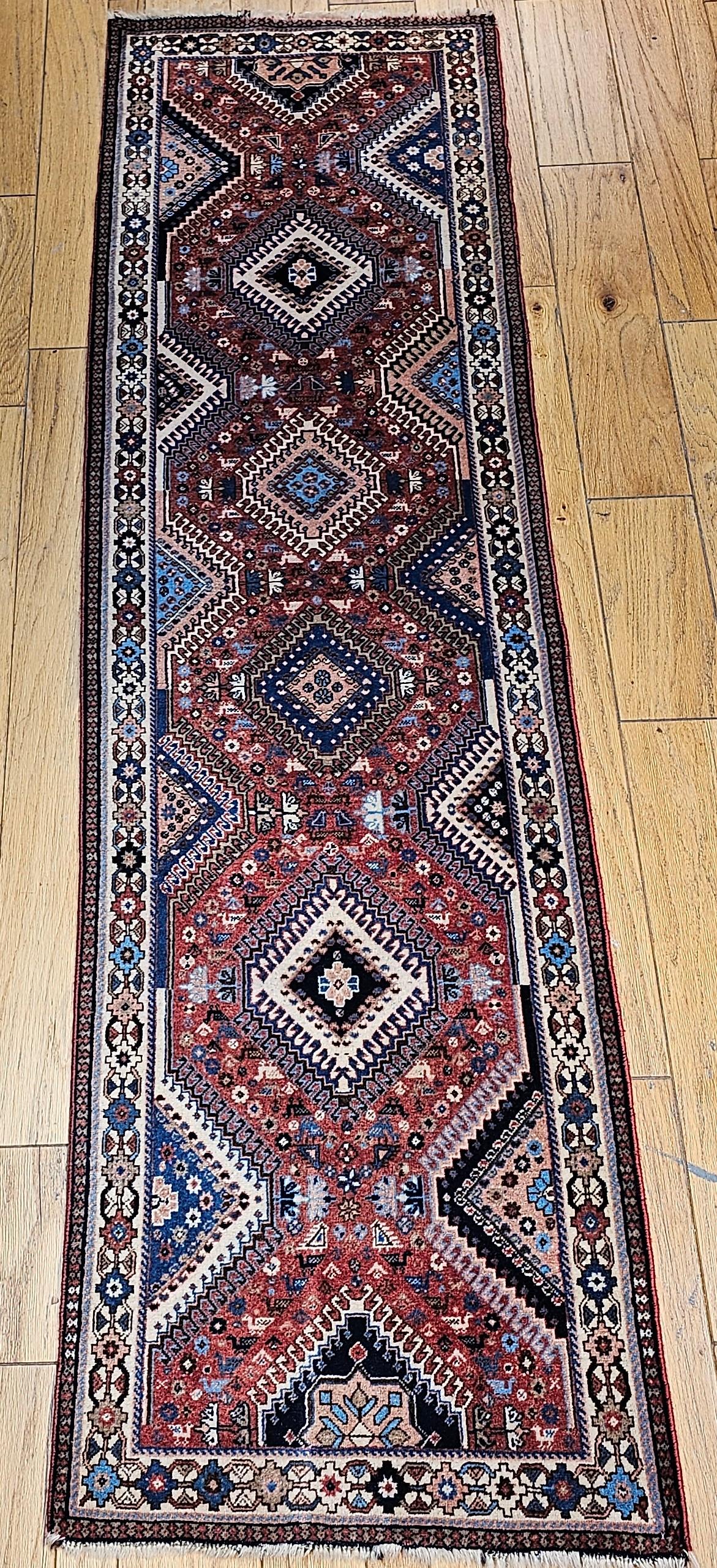 Vintage Persian Shiraz Yalameh Stammes-Läufer in einem geometrischen Allover-Muster in den Farben Rot, Elfenbein und Blau.  Das Design besteht aus einer einzigen Säule von miteinander verbundenen Riegelhakenmedaillons in leuchtenden Farben von Gelb