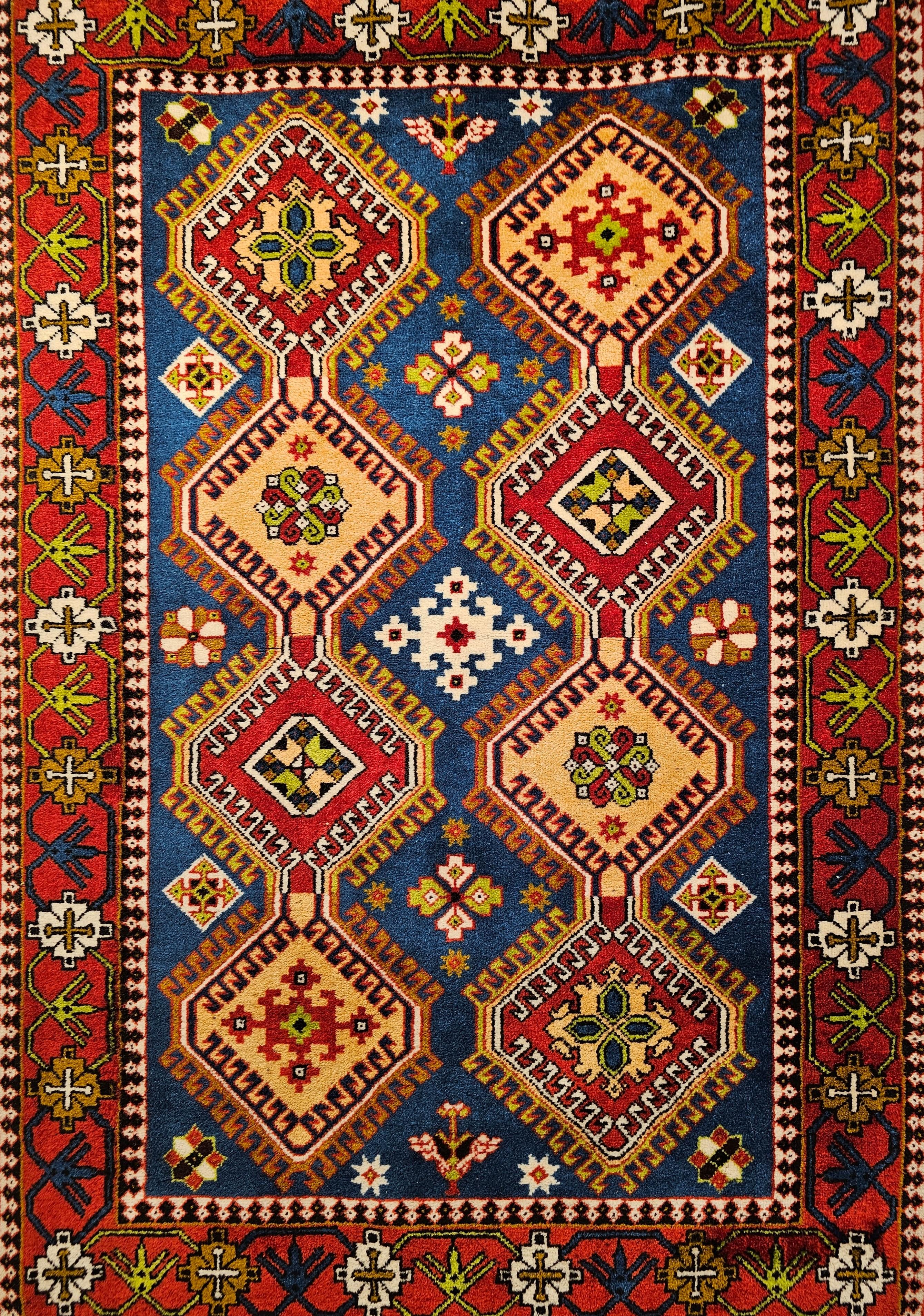 A beautiful mid century Persian Shiraz Yalameh tribal rug in a geometric allover pattern  in French blue,  red, yellow, and ivory colors.  The design consists of two columns of connected latch hook medallions in bright colors of yellow, and red set