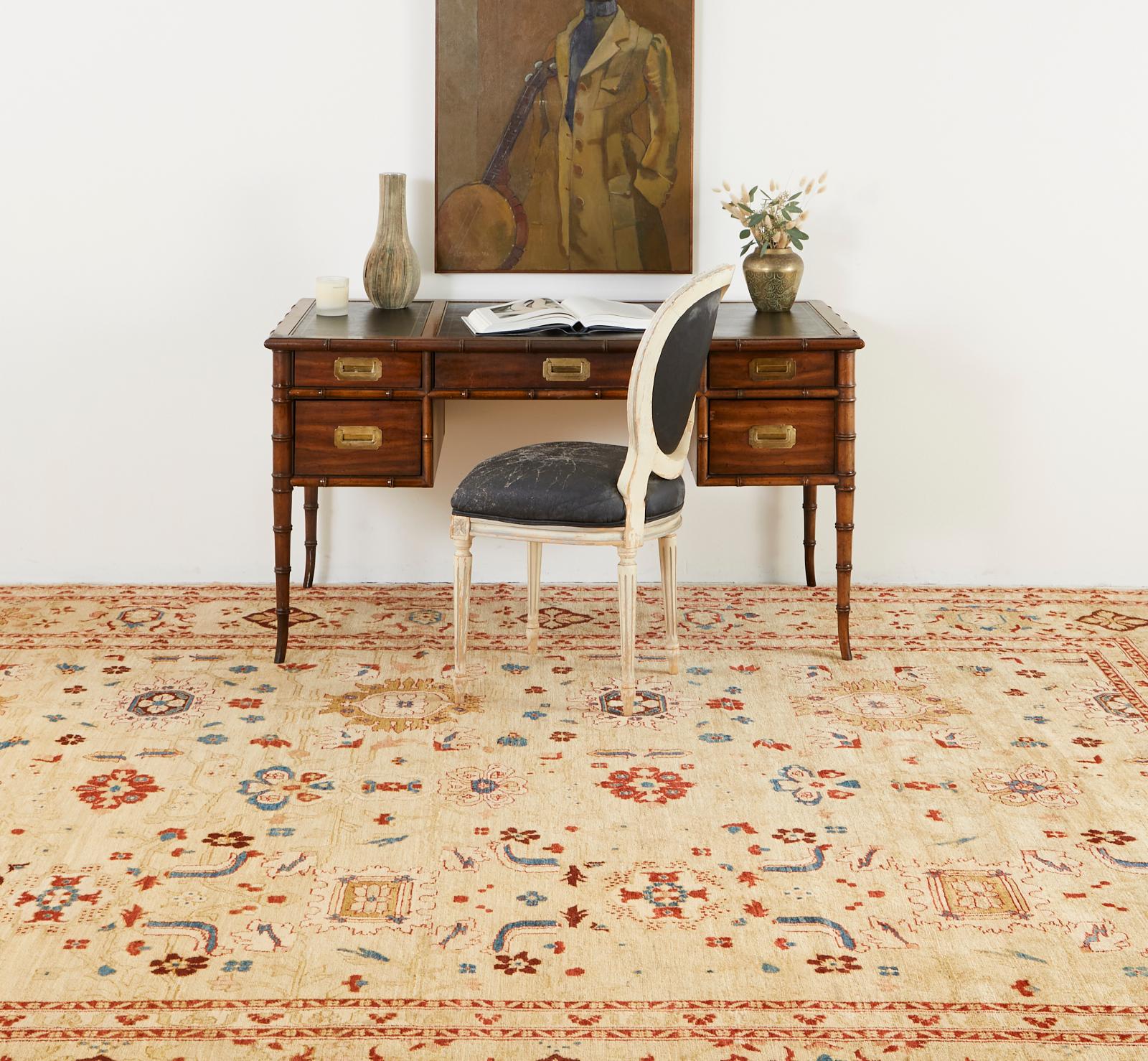 Traditional style Persian Sultanabad carpet featuring a light camel colored field decorated with larger floral and vine motifs. The rug is signed by the weaver in a panel on bottom. The rug has vibrant jewel tone blue, red, and maroon colors with