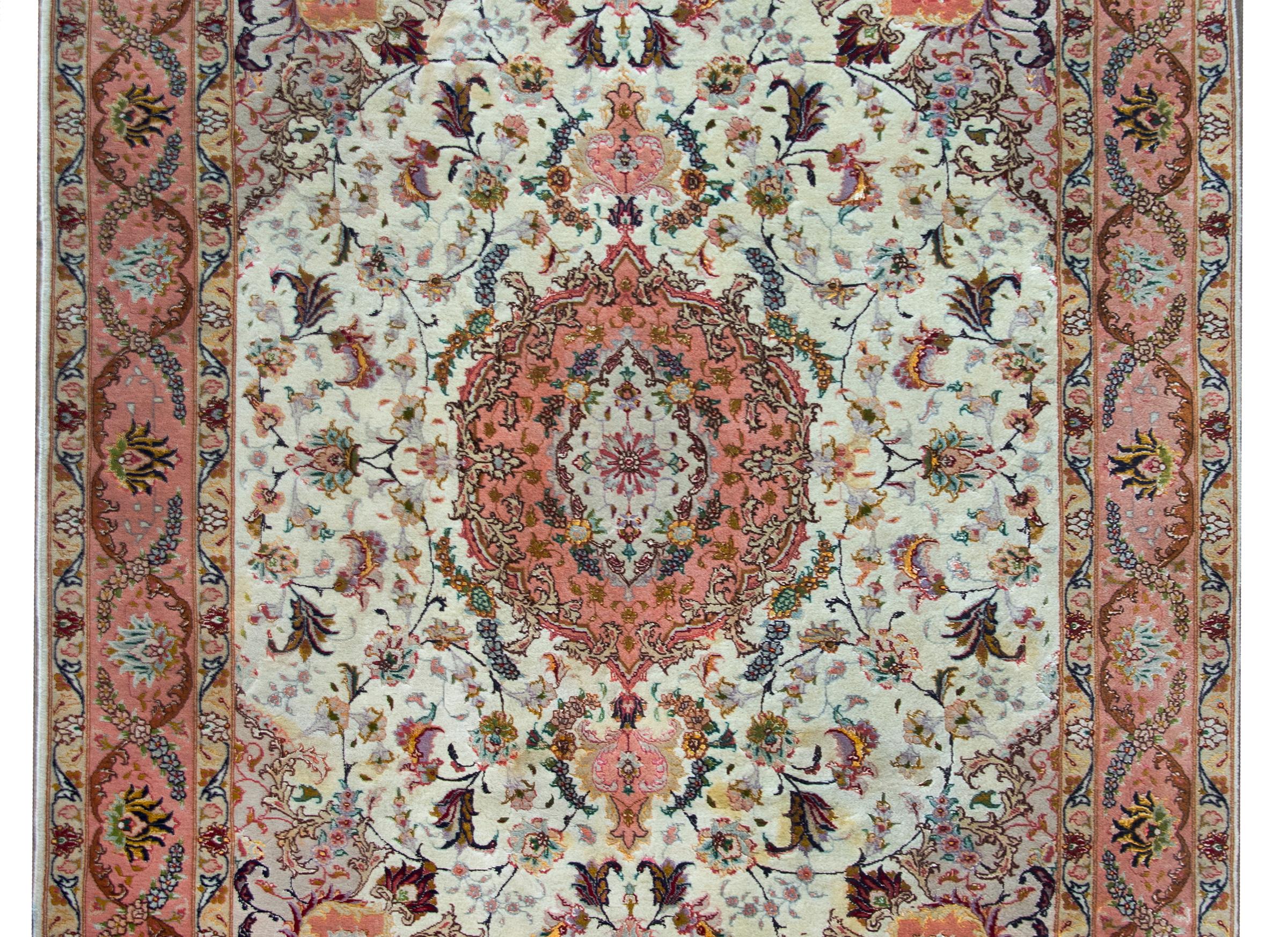 A remarkable 20th century Persian Tabriz rug with a large central floral medallion living amidst a field of even more flowers and vines, and surrounded by a sensational elaborately woven floral patterned border, and all woven in cheerful pinks,