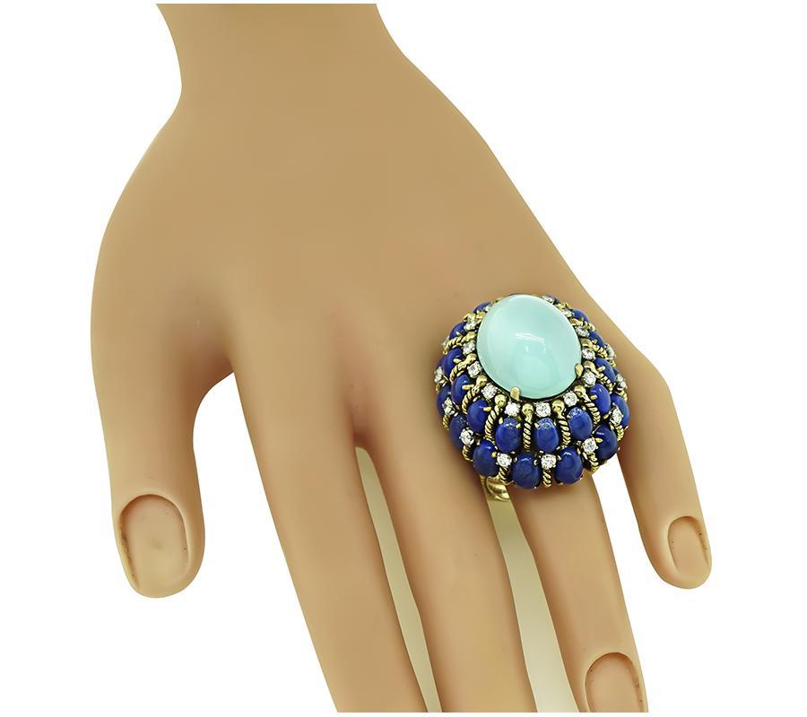 This is an elegant 14k yellow gold ring from the 1960s. The ring is centered with lovely cabochon Persian sleeping beauty turquoise. The center stone is accentuated by cabochon lapis and round cut diamond accents. The top of the ring measures 35mm