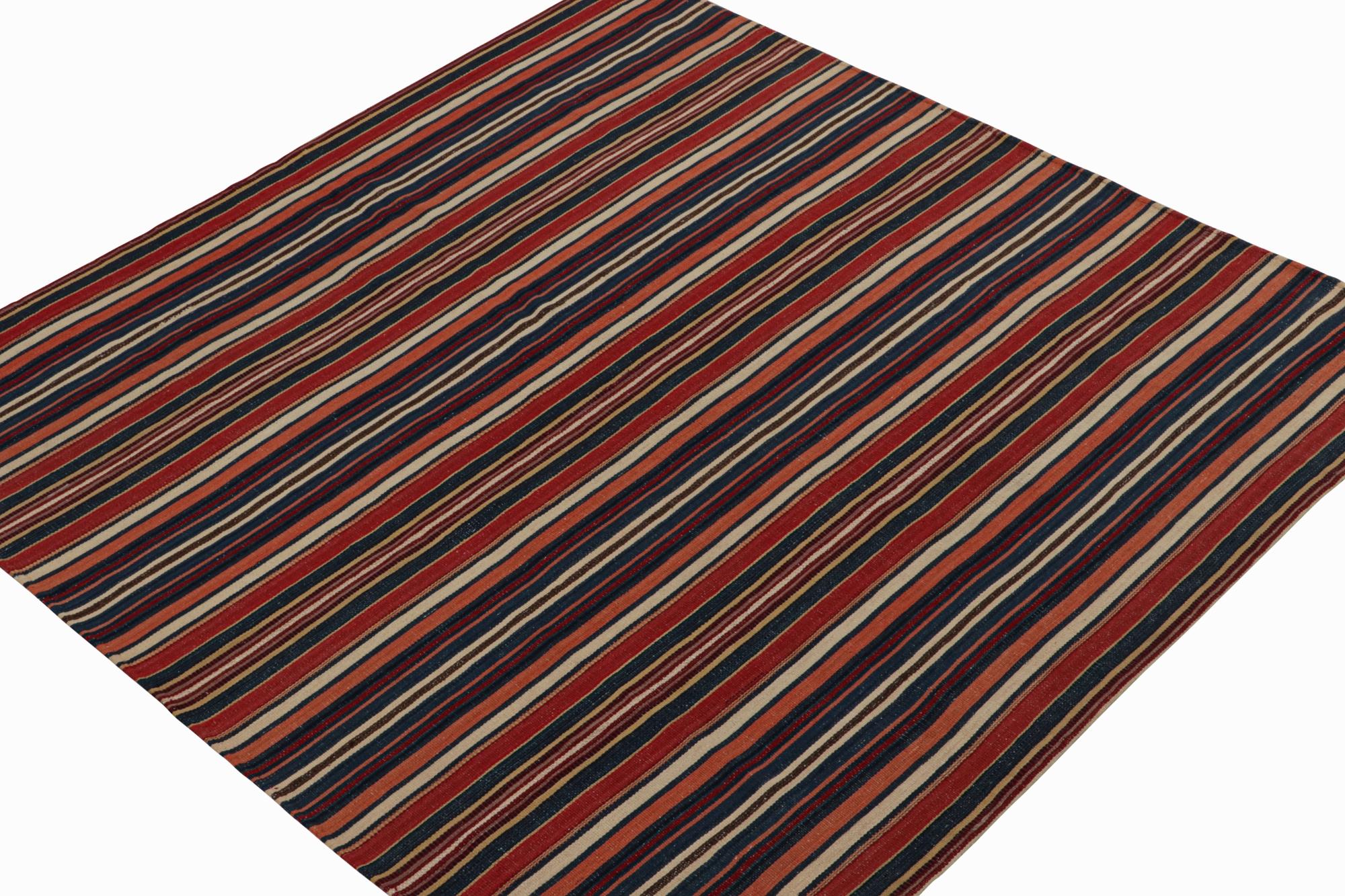 This vintage 7x7 Persian Kilim is handwoven in wool, and originates circa 1950-1960.

On the Design: 

This flat weave carries stripes in a repeat all over pattern with rich red, beige and brown tones. Keen eyes may note salmon and navy blue