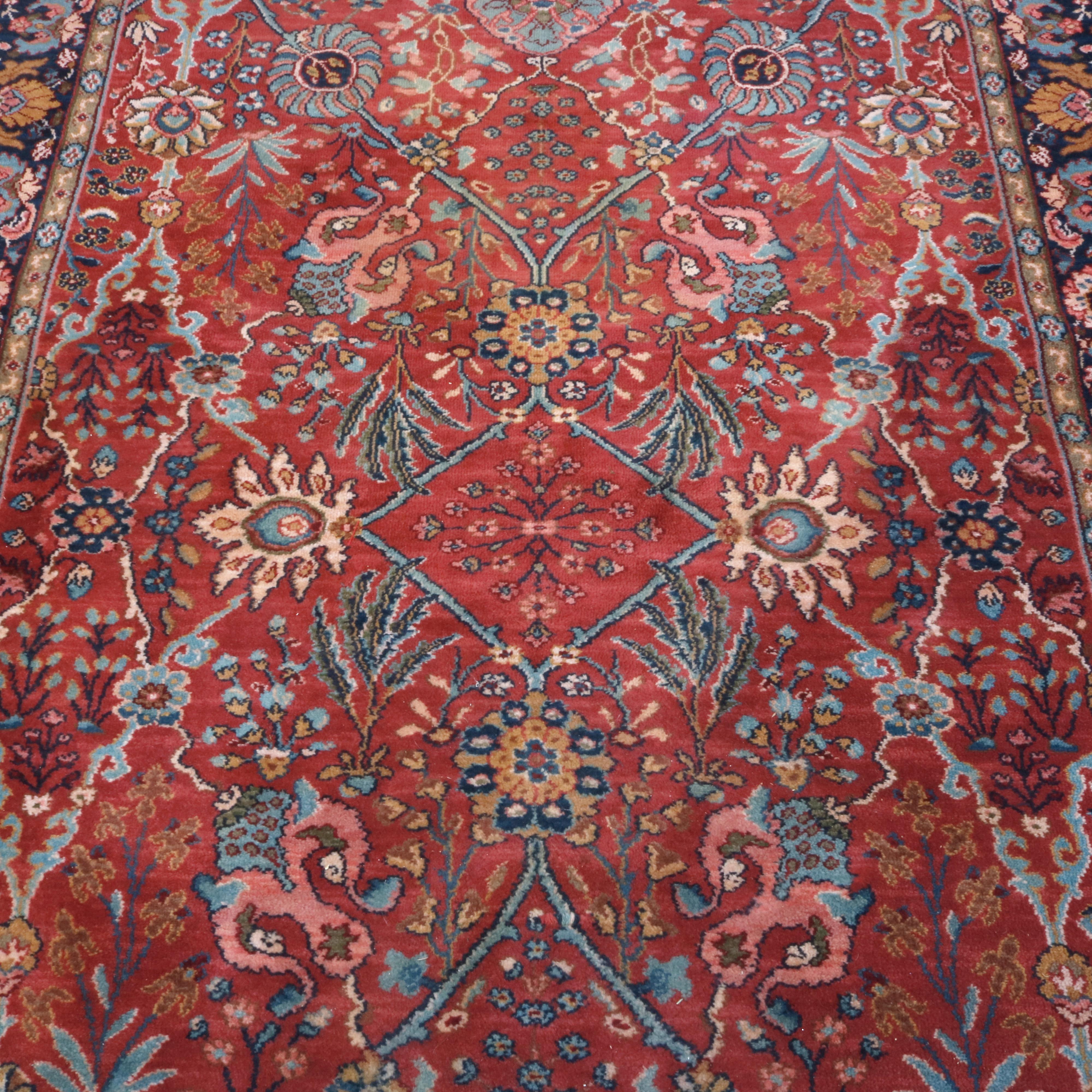 A vintage Persian style oriental rug offers wool construction with floral, scroll and foliate motif on red ground, 
