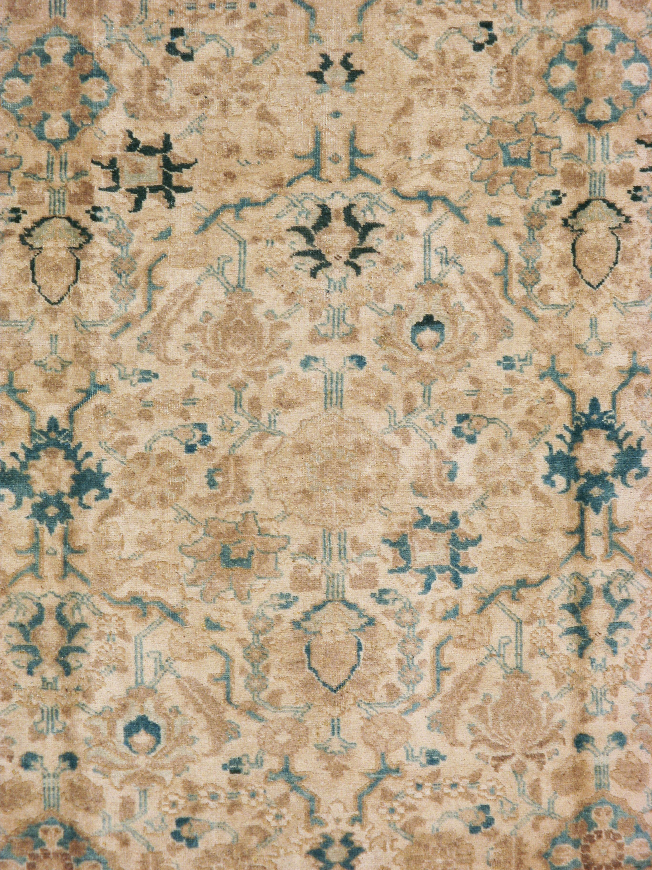 A vintage Persian Tabriz carpet from the mid-20th century. The ivory field is designed by vines and floral arrays in shades of seafoam green, blue, and light brown. The border used a reverse color palette to contrast gently against the field.