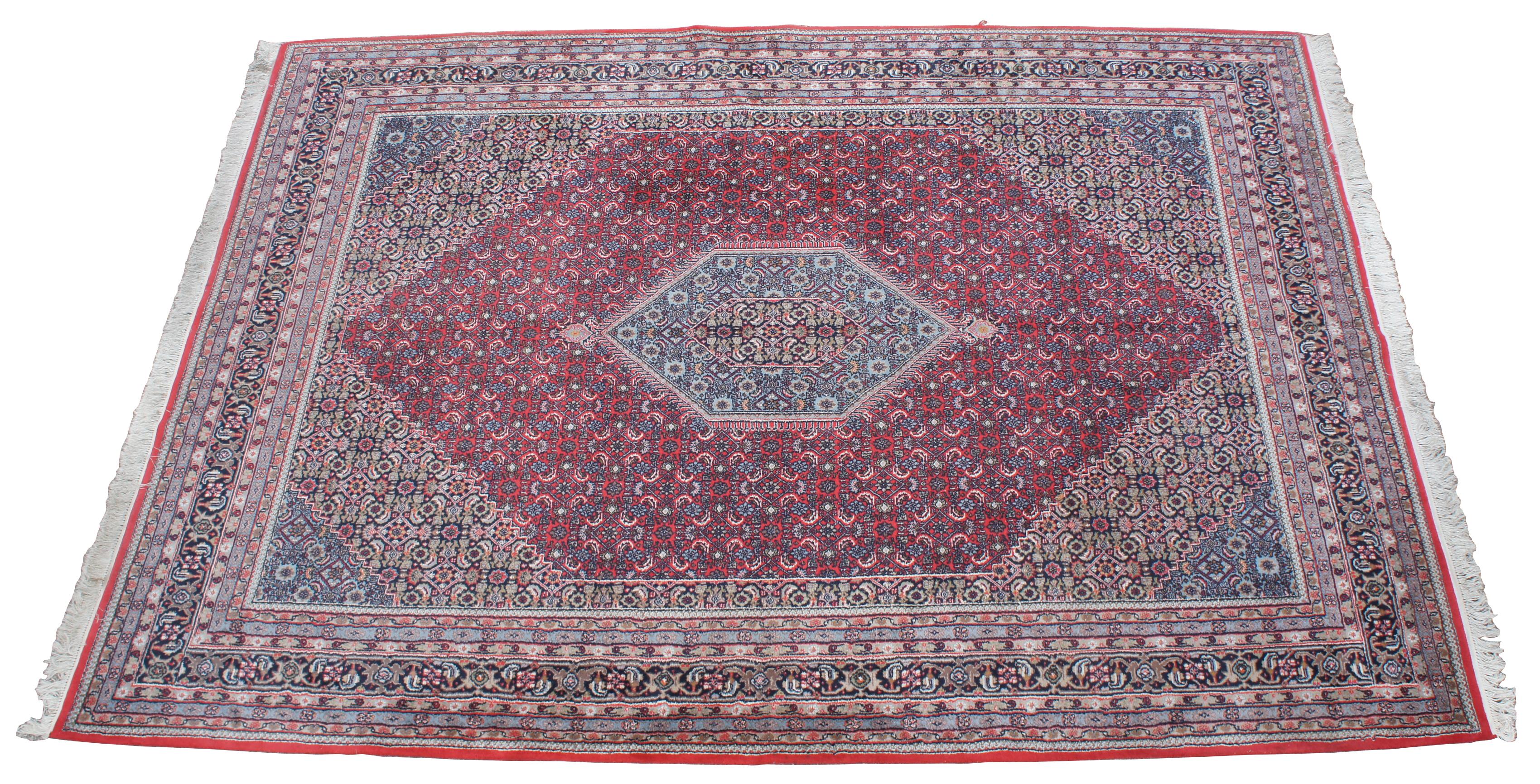 Vintage Persian Tabriz Mahi medallion area rug. Featuring a field of reds, with a central geometric shaped medallion with blues, brown, pink, green and orange accents. Made of wool in the city of Tabriz, east of Azarbaijan Province in north west