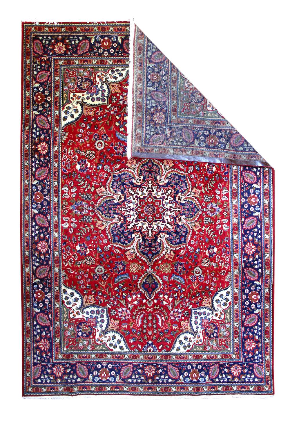 Tappeto persiano Tabriz vintage 6'7'' x 9'10''. In un elaborato stile Heriz, con un campo rosso centrato da un medaglione navy a otto lobi con pendenti en suite. Gli elementi floreali di supporto hanno un deciso aspetto Heriz. Angoli ecru con
