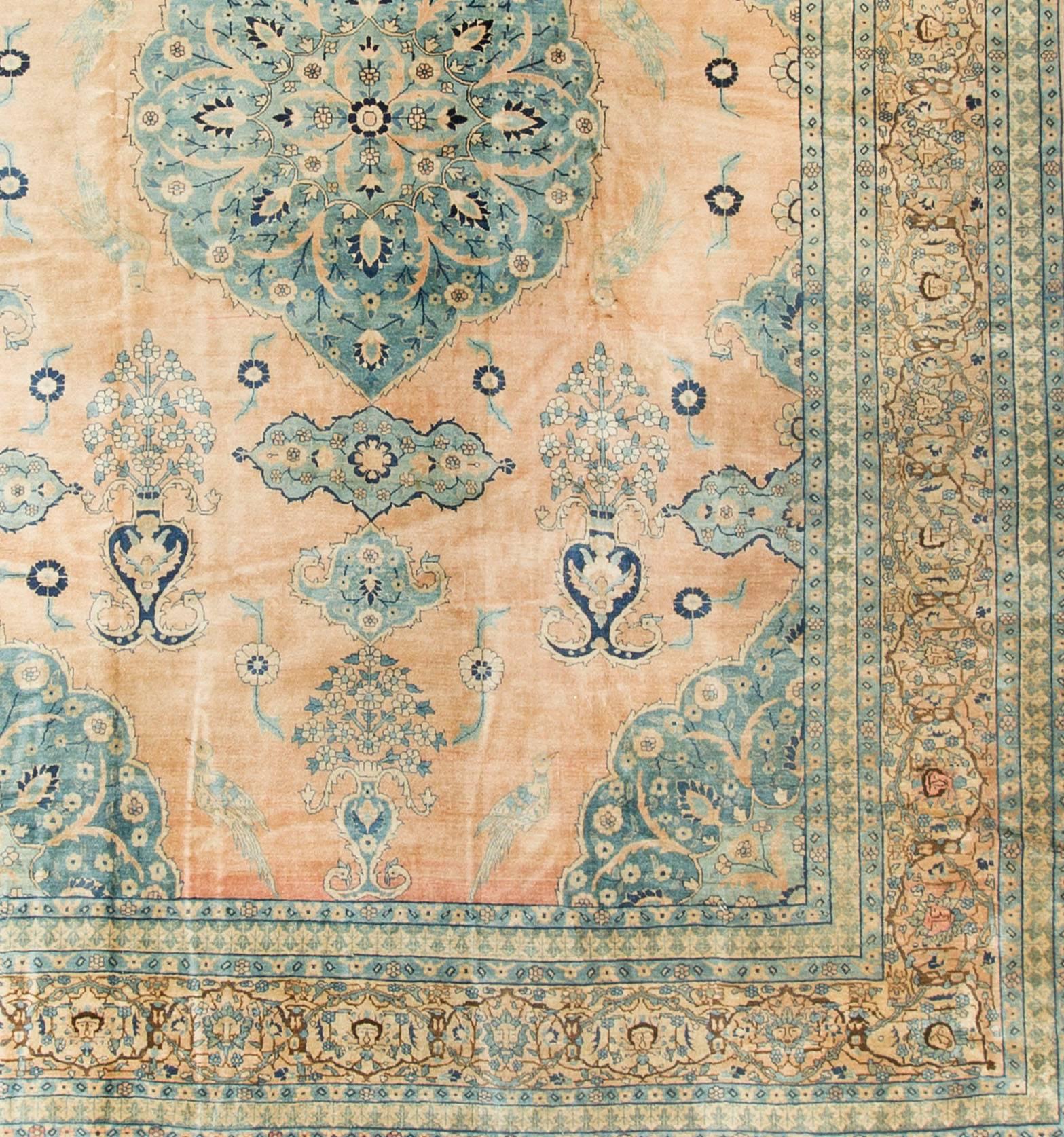 A vintage circa 1940s Persian handwoven Tabriz rug. The soft pastel peach-rose colored field adds a lightness to the rug that the darker central medallion enhances. All enclosed within a main border repeating the soft colors and multiple guard