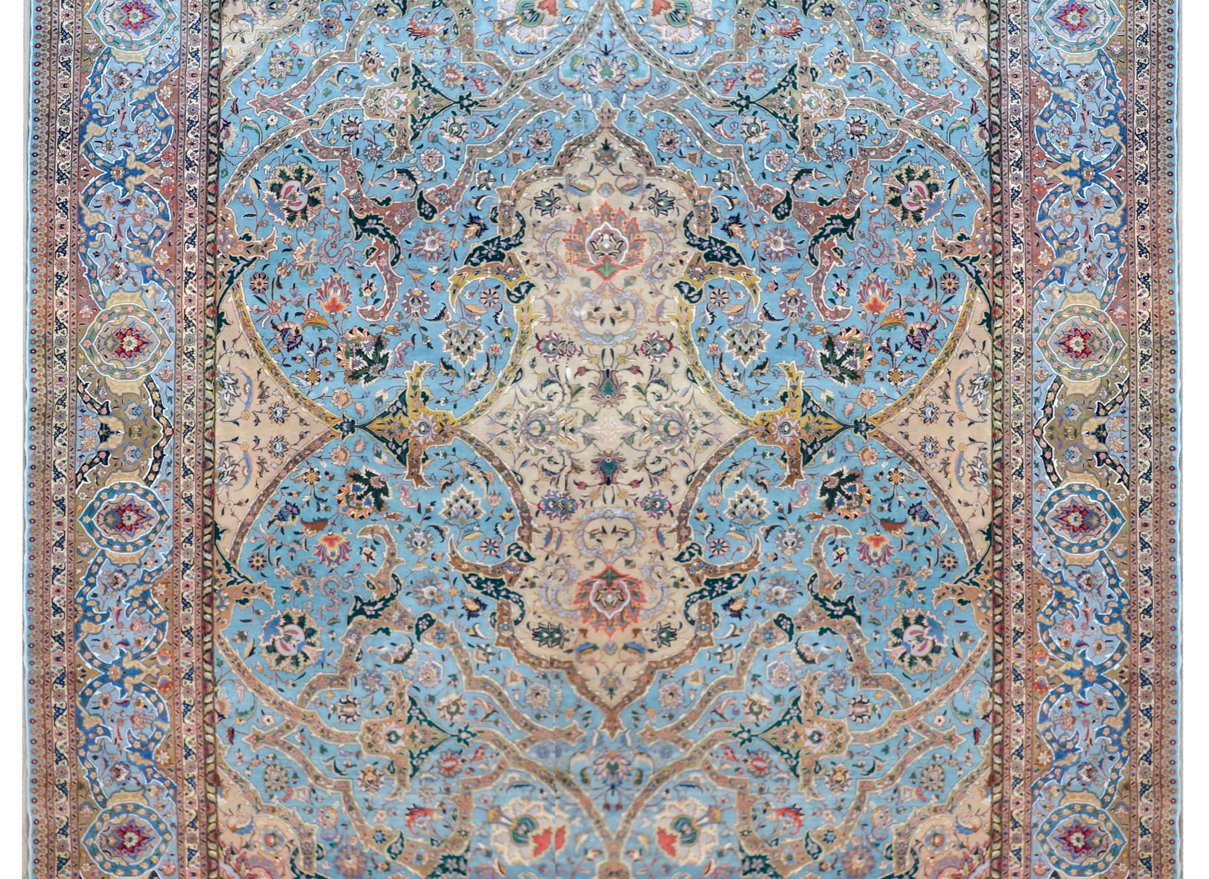 An incredible vintage Persian Tabriz rug with an unusual pattern containing a large central medallion with flowers woven in soft pastel colors set against a field of more flowers, and all set against a bright light indigo background. The border is