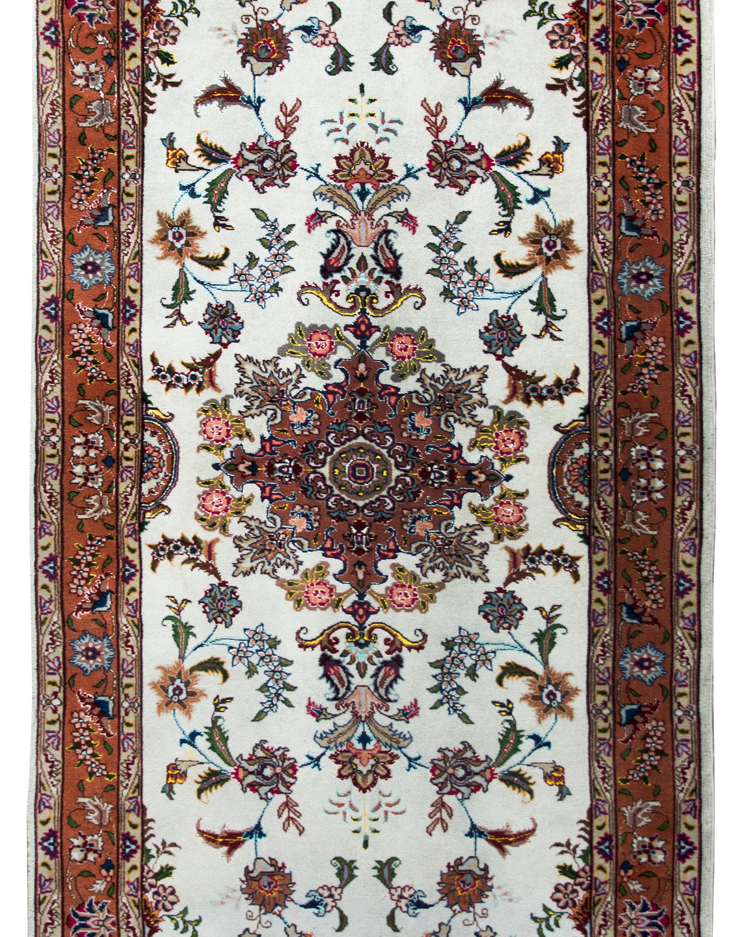 A wonderful vintage, late 20th century, Persian Tabriz rug woven in silk and wool, and with a large central floral medallion living amidst a field of more flowers and vines, and surrounded by a wide complex border with even more repeated flowers and