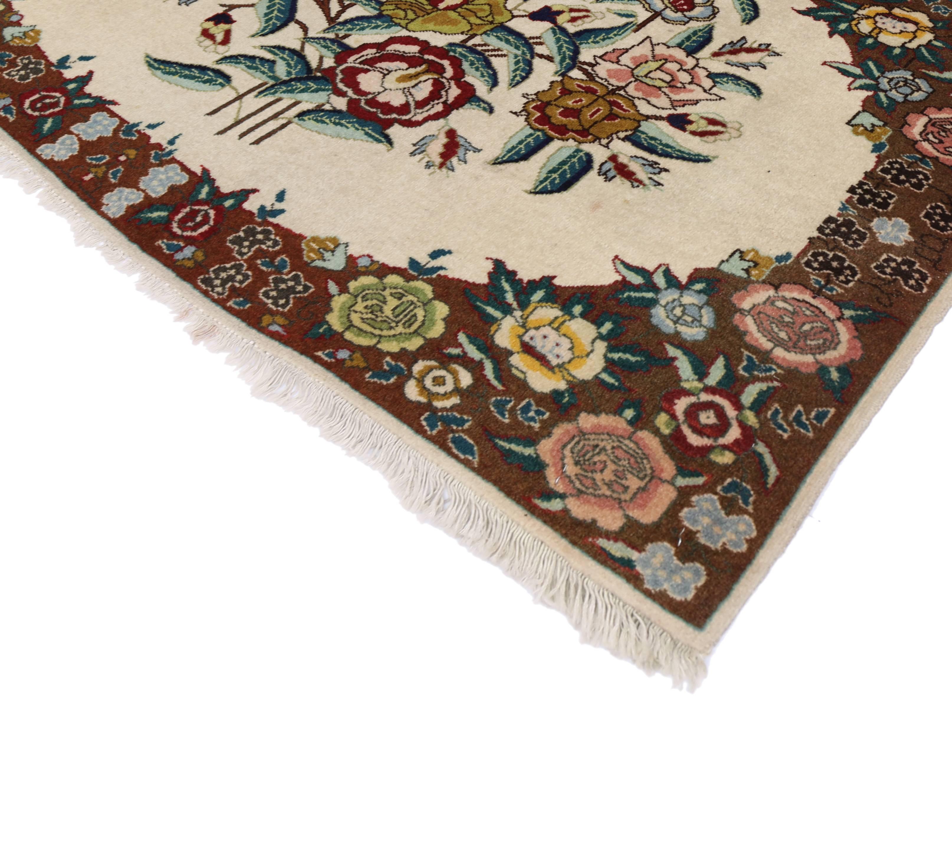 75654, vintage Persian Tabriz rug with traditional style. This hand-knotted wool vintage Persian Tabriz rug features a floral bouquet in a creamy vanilla field surrounded by a complementary floral border creating a well-balanced and timeless design.