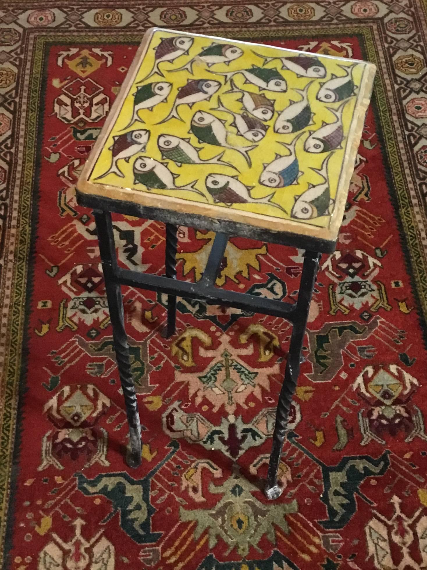 Elegant side table made of ceramic Persian tile top hand-painted and glazed of a wondering school of fish on a beautiful yellow background. The base of the table made of iron with four hand
twisted legs, very decorative and functional side table