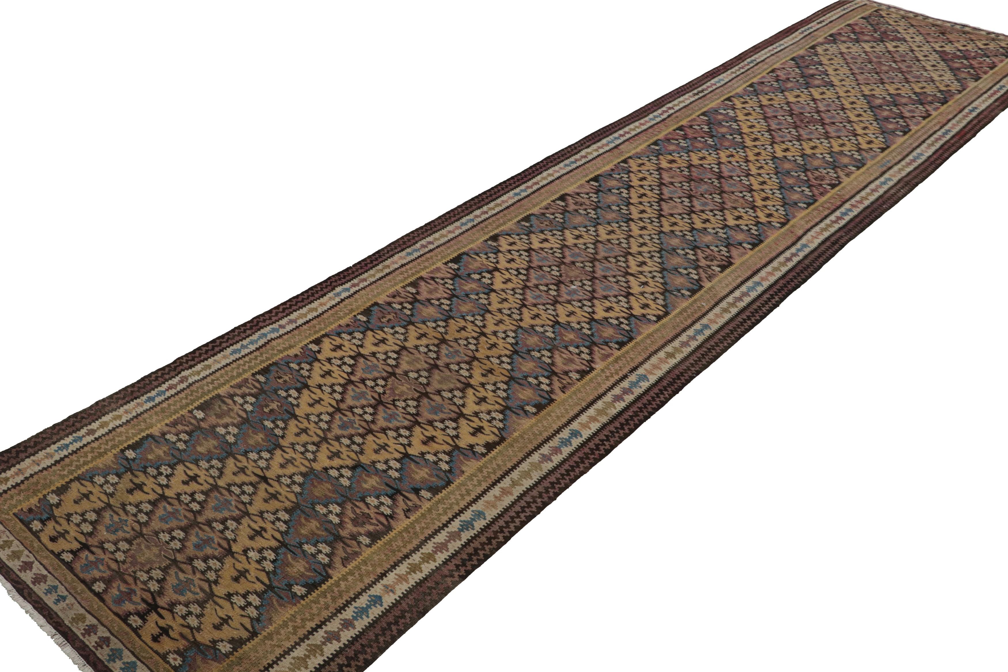 Handwoven in wool circa 1950-1960, this 3x15 vintage Persian tribal Kilim and extra-long runner rug is a rare curation. Its design enjoys mosaic-like geometric patterns in gold, beige-brown, blue and pink, resembling those of a rare limited series. 